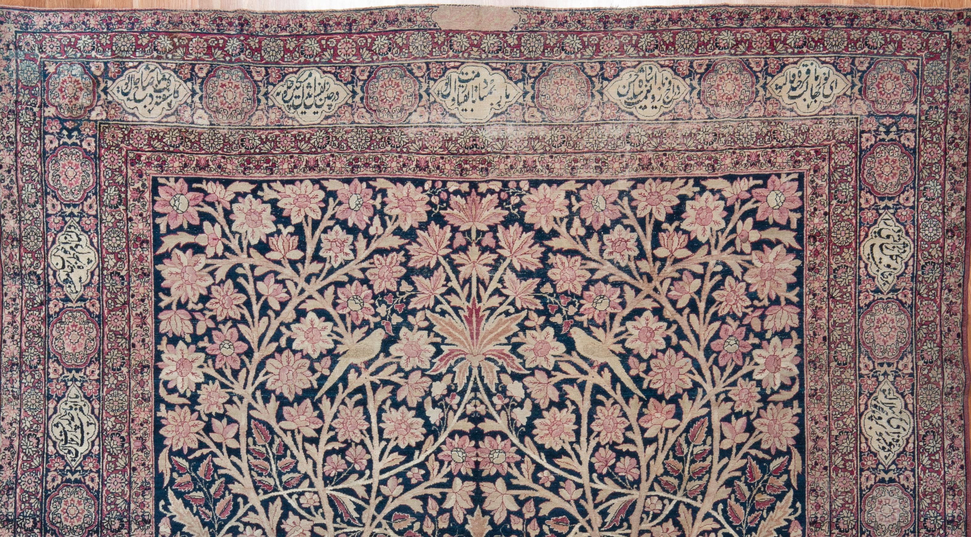 An intricately woven carpet from the late 19th Century, this Persian Lavar has a gorgeous botanical design of climbing vines, flowers and birds in mauve, soft pink and ivory set on a deep navy field. A very low wool pile. Naturally dyed. An heirloom