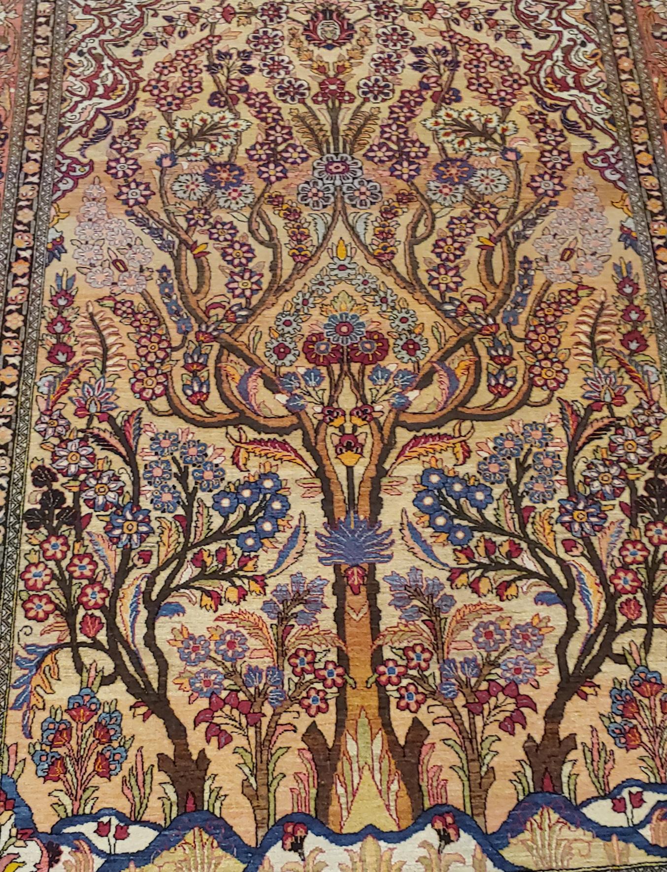 This is a rare Tree of Life motif Persian Lavar Kerman. Lavar means very Fine and became an actual title for these very Fine Kerman's woven in the early 20th century. The colorful tree covers a gold/tan field with a soft red border. It is in very