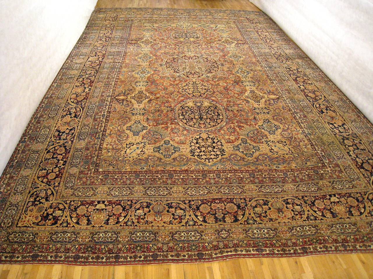 A magnificent oversize antique Persian Lavar carpet, circa 1880. Size: 24'5 x 15'3. This lovely carpet has a series of medallions on an intricately woven soft red central field, with beautiful navy outer border. This rug is extremely finely woven,