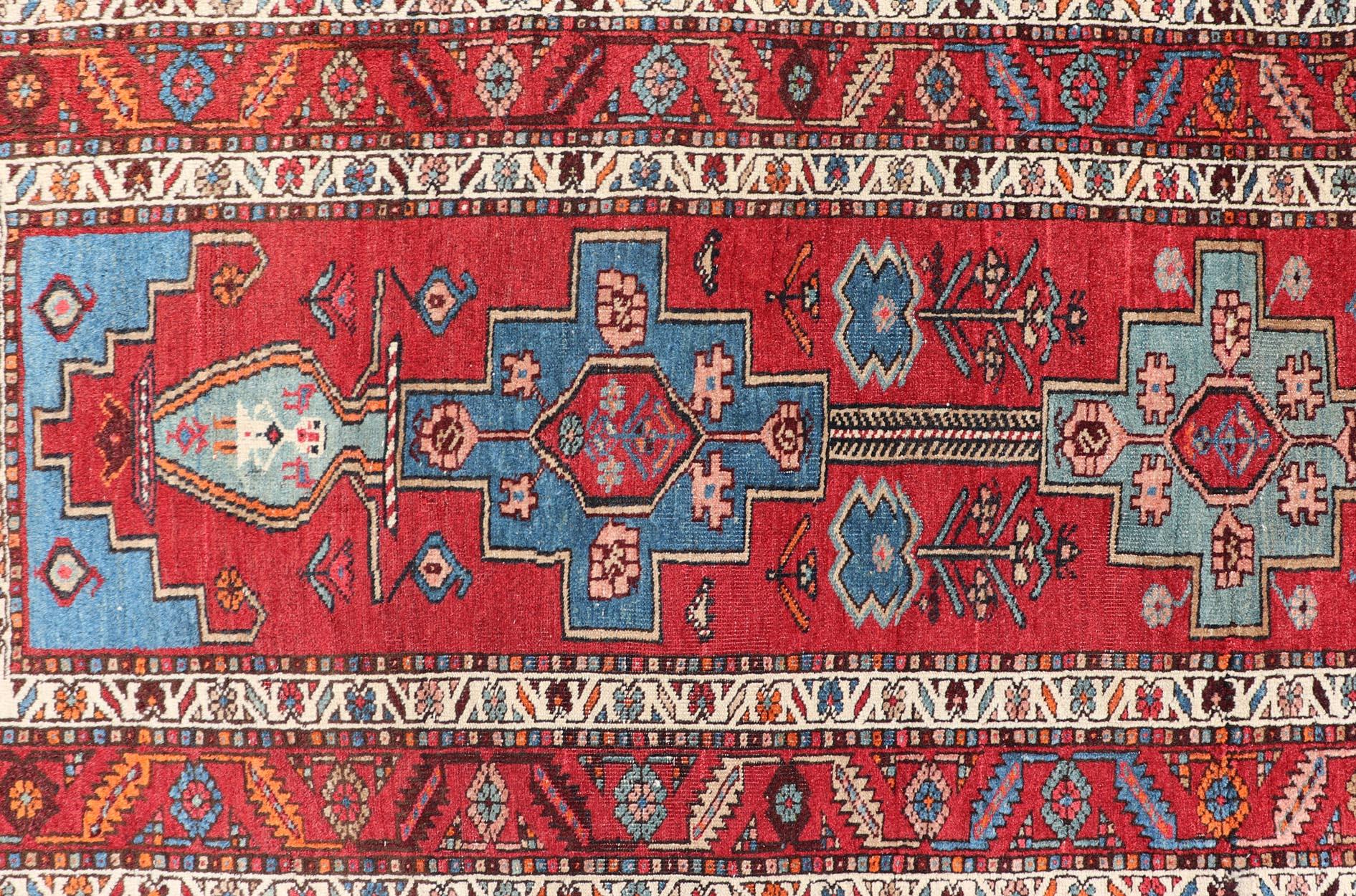This antique Persian Serapi rug was hand-knotted in wool and features a sub-geometric medallion design rendered in multicolor. A complementary, multi-tiered border encompasses the entirety of the piece; making it a marvelous fit for a wide variety