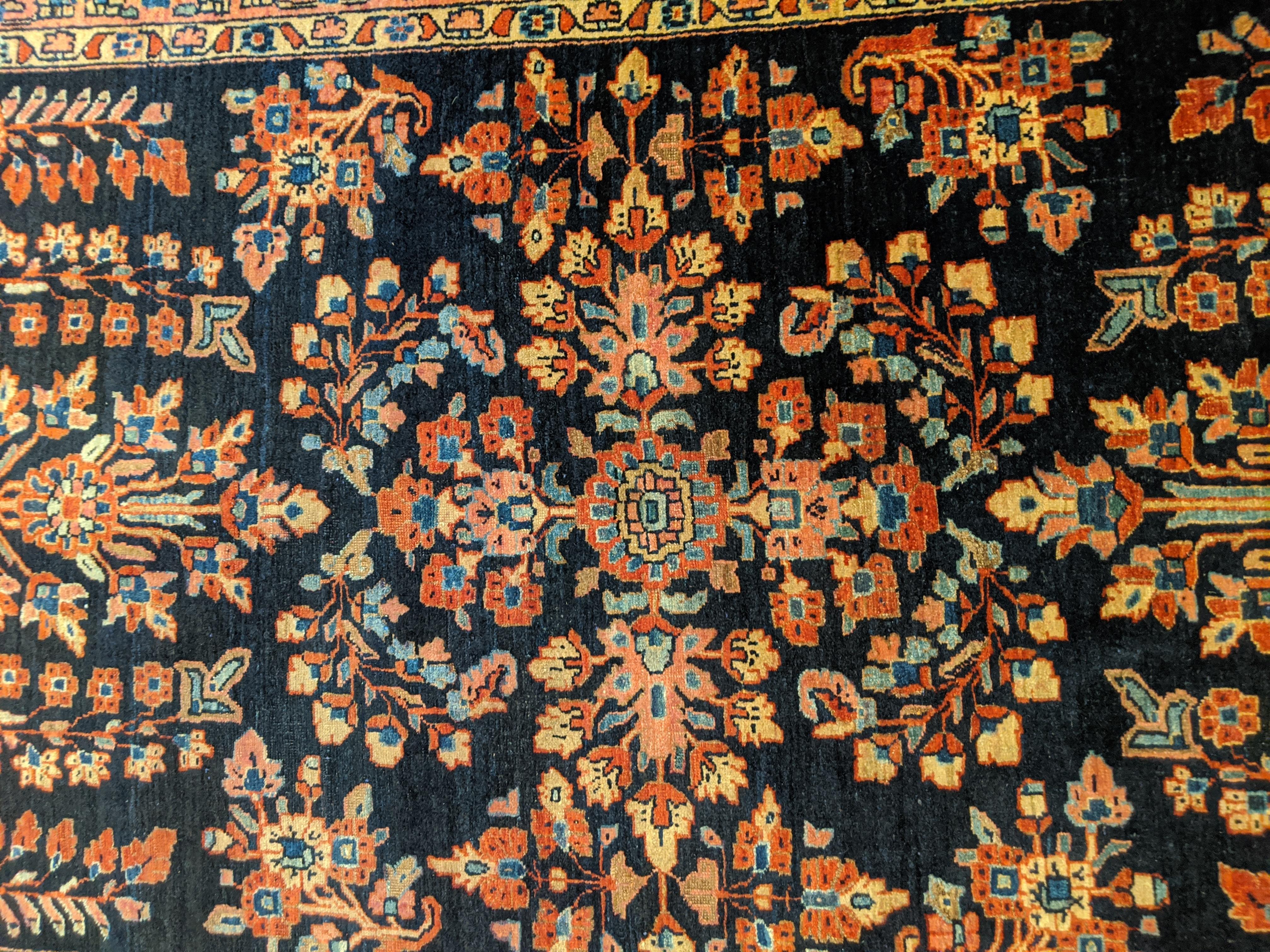 This is a wonderful antique Persian Mahadjeran Sarouk with a navy field decorated with a floral motif in light blues, tans and golds. It is 3 x 5-1 and is circa 1915. Mahadjeran, also spelled Mahajiran or Mohajeran is a name given to a select few