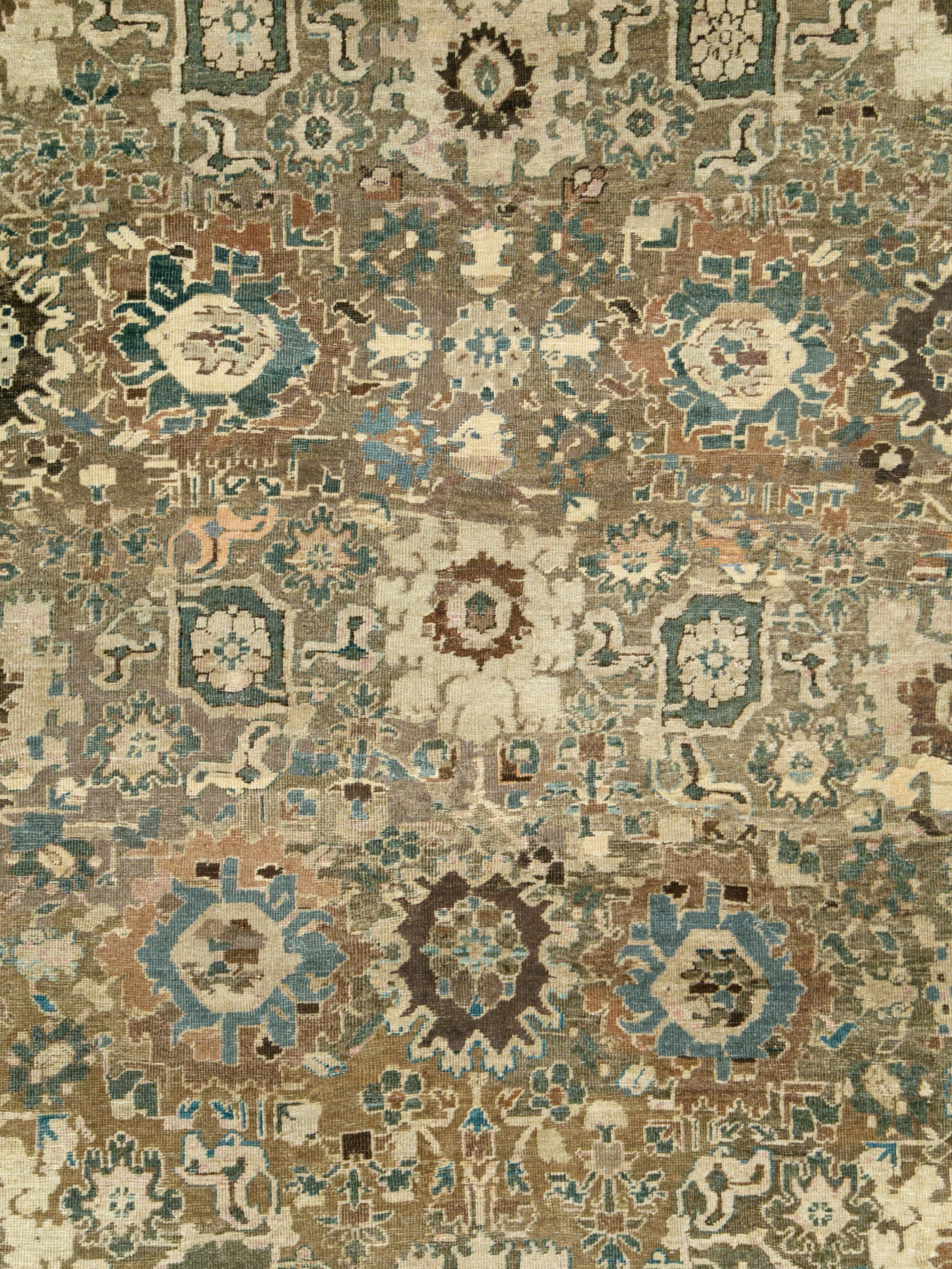 An antique Persian Mahal carpet from the early 20th century with the Classic Persian Harshang (crab) pattern of ragged palmettes, fringed rosettes, oblique ellipses, and flower arrays, all detailed in ivory and slate. The abrashed (natural color