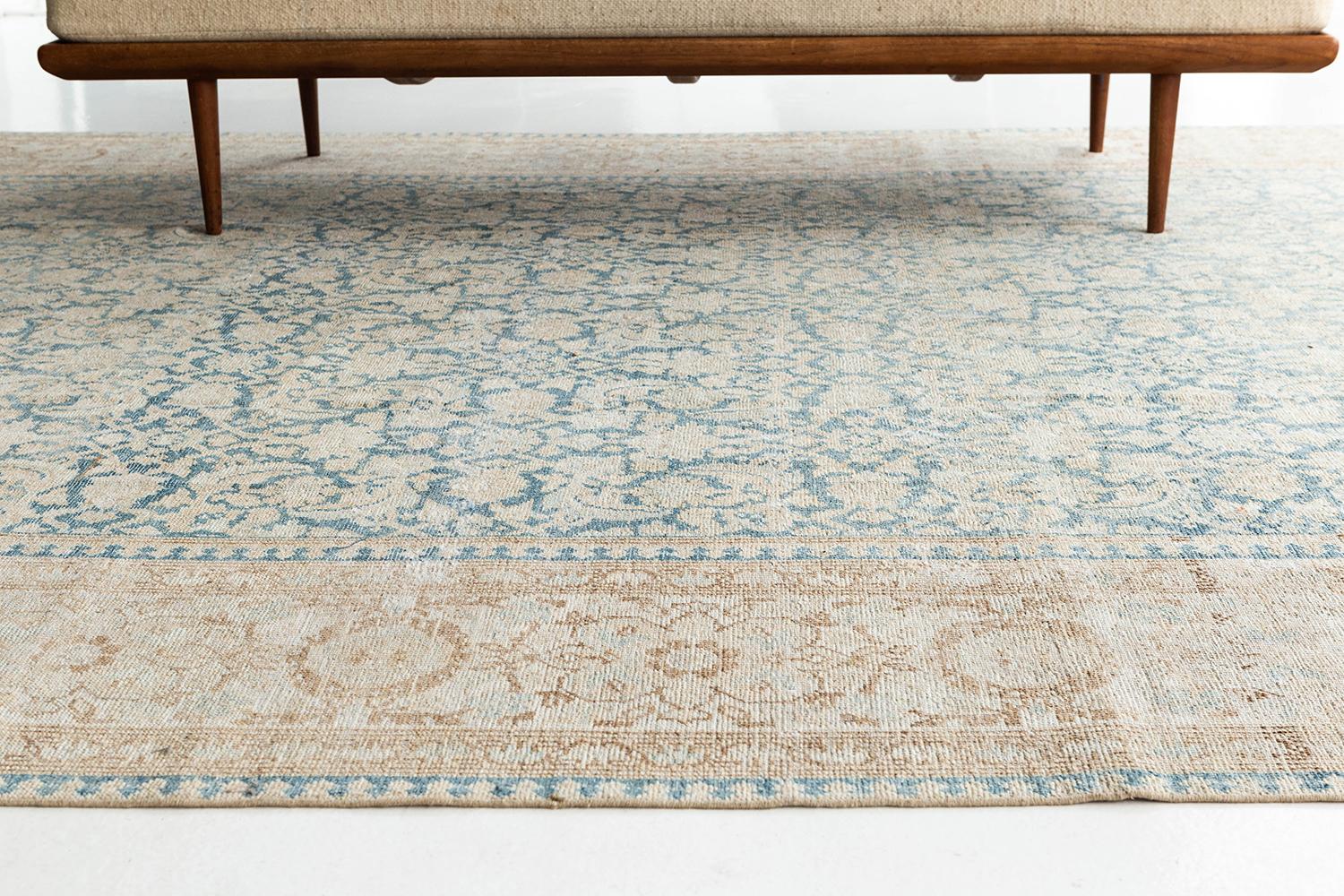 An antique Persian Mahal that is the epitome of elegance and timelessness. This Mahal features an elegant and classical all-over pattern of flowering vines and unfolding scrolls. The rug's blue, tan, and ivory colors allow for lots of versatility in