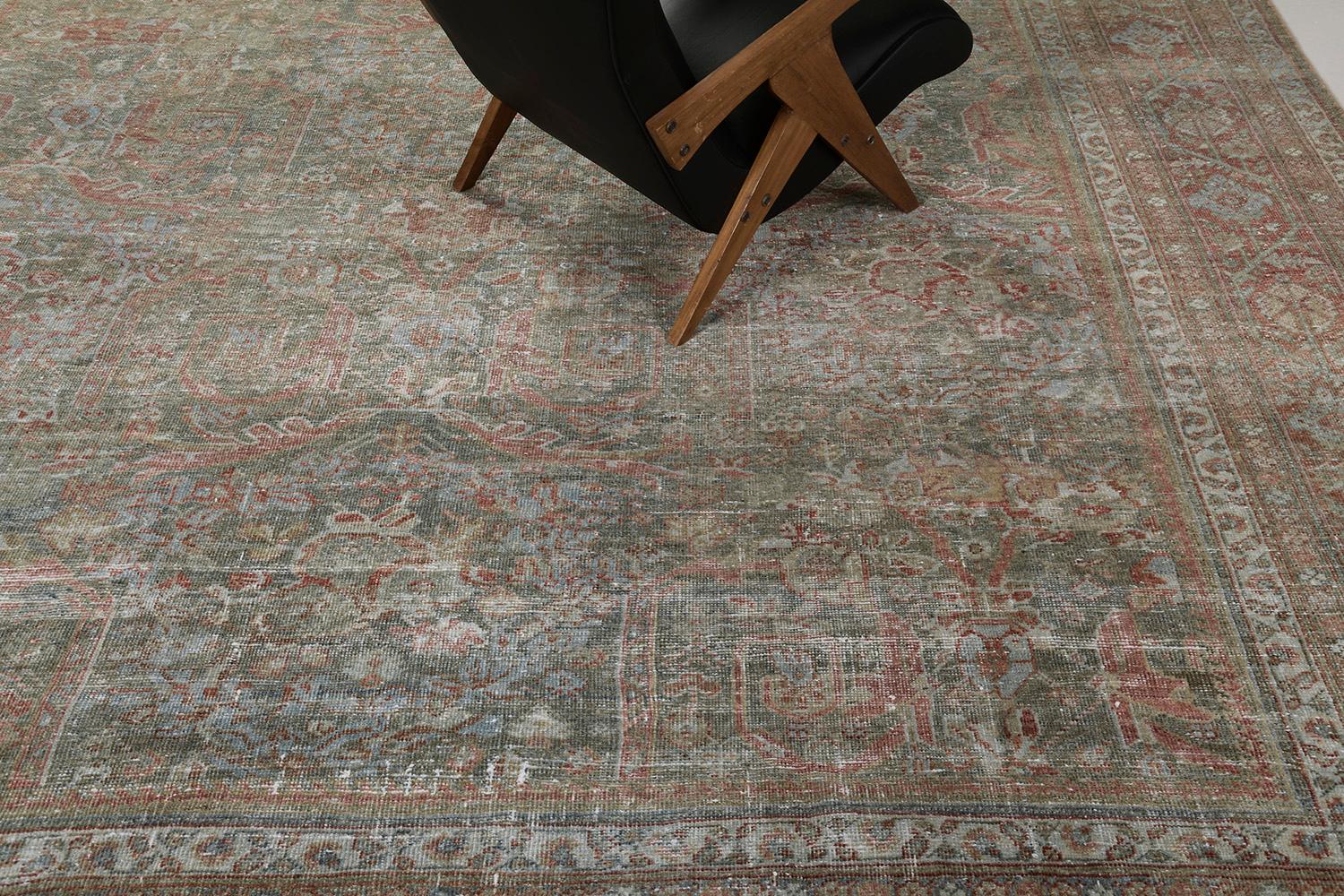An exquisite antique Persian Mahal rug that features timeless grace and nostalgic appeal. This enchanting rug is enclosed with a botanical border flanked with inner and outer guard bands. The abrashed terracotta field is graciously filled with