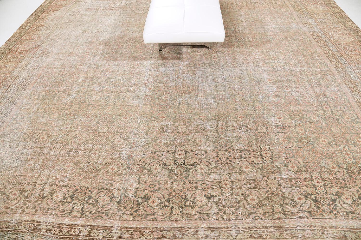 A captivating Antique Persian Mahal rug that charms you to an all-over pattern of botanical elements that is spread gracefully throughout the rust field. This fascinating rug is covered by majestic patterns of stylized patterns and alluring