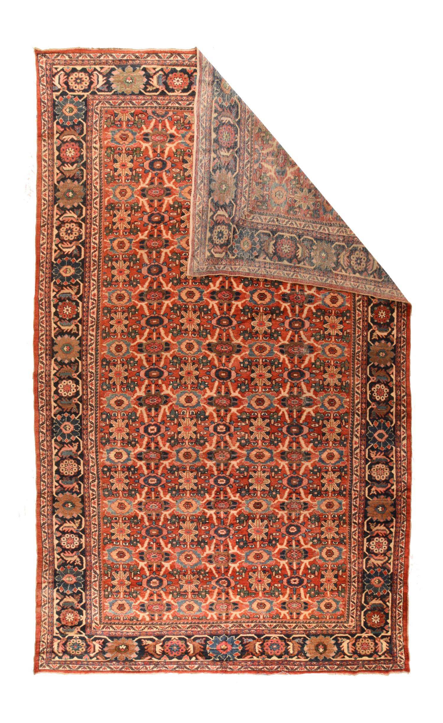 This soft red madder ground West Persian village large carpet shows an allover rendition of the popular Mina Khani rosette lattice trellis with cream circles, straw rosettes, and green and teal details. Characteristic dark blue border with angular