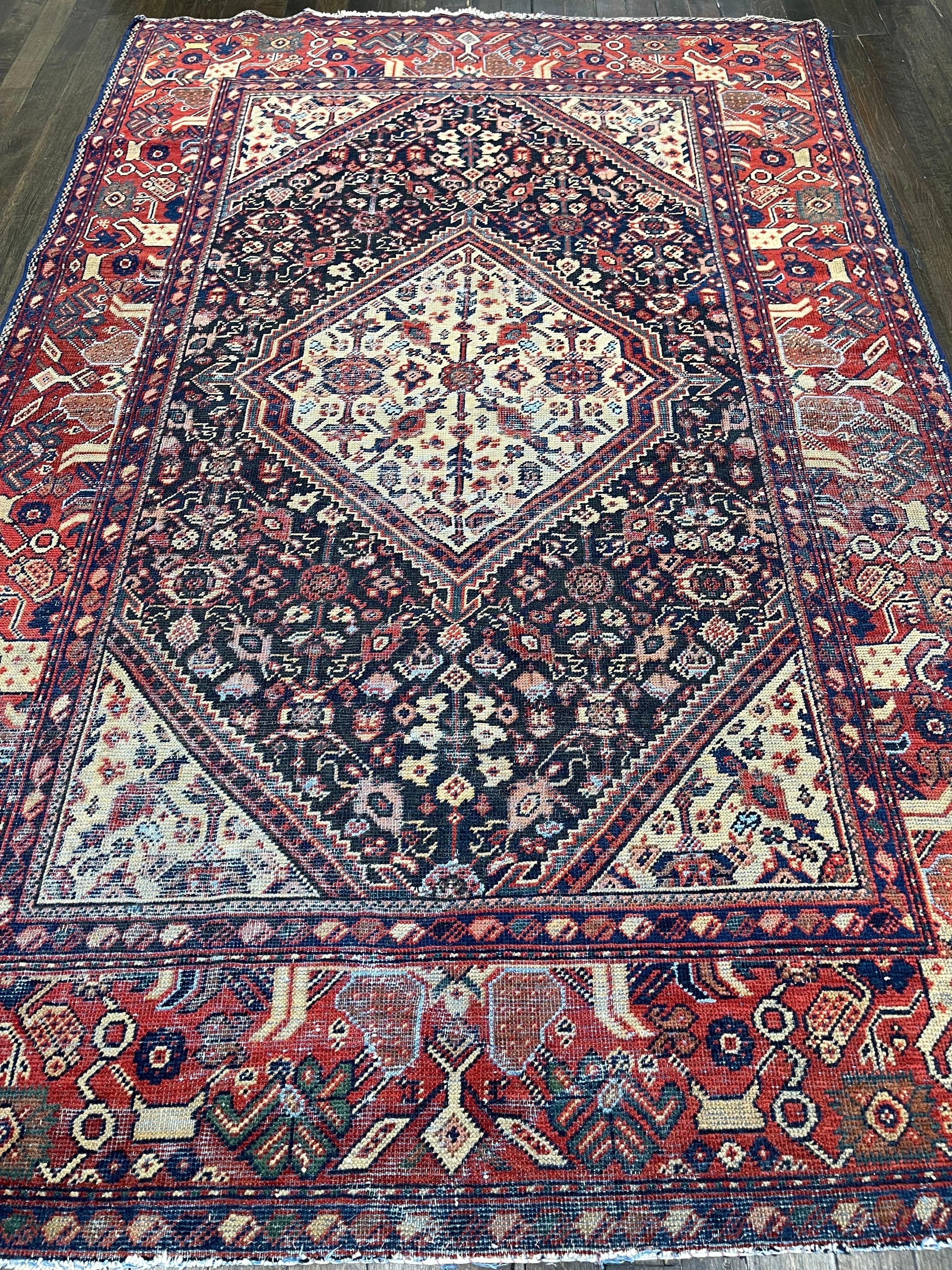 A rustic antique Persian Mahal, this rug is an attractive accent piece having a navy blue field closely covered by a medium scale classic Herati pattern. An authentic turn of the century distressed carpet with very low pile that has maintained its