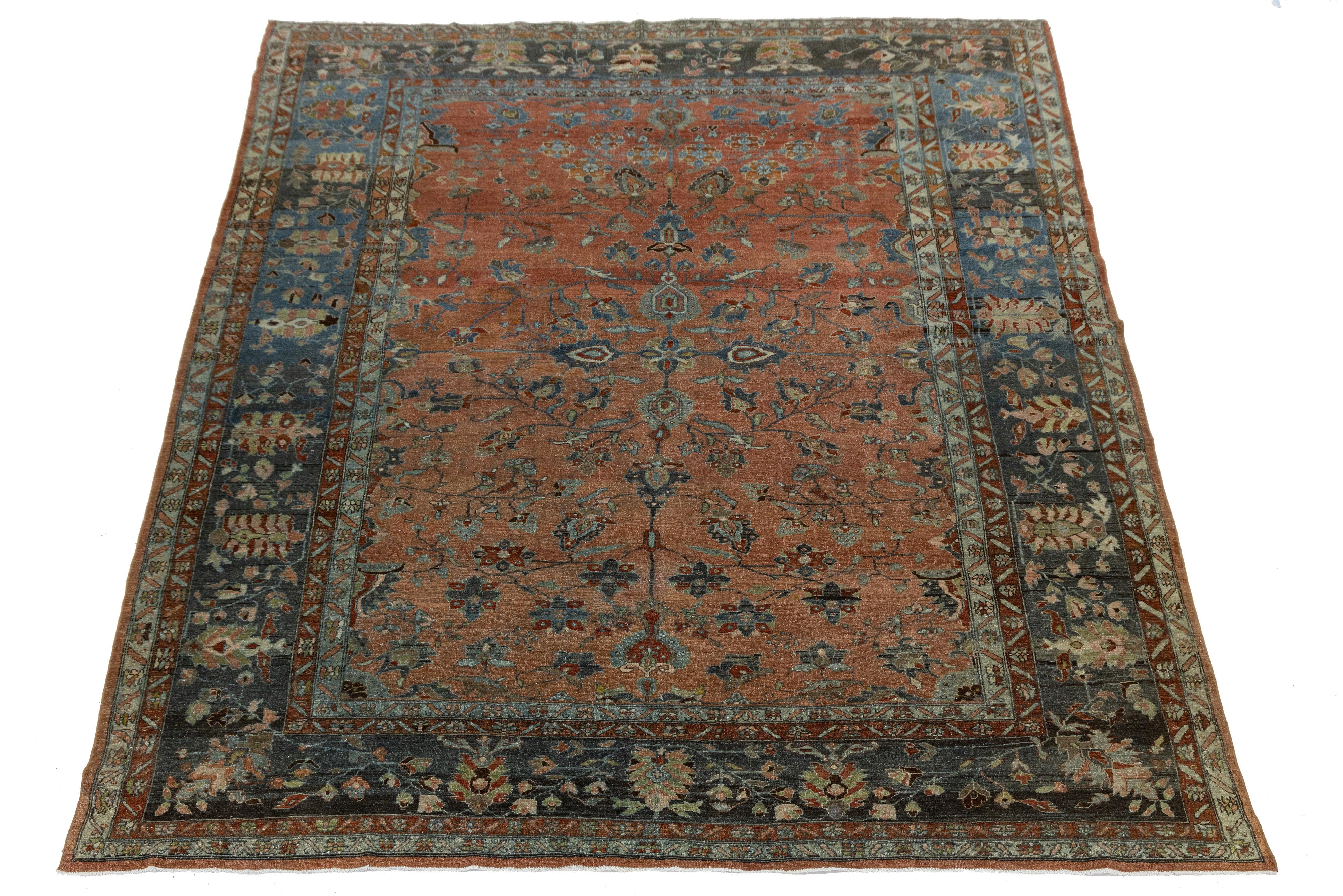 Elegant antique Persian Mahal rug, hand-knotted in wool with a muted red field and intricate floral-geometric motifs in ivory, blue, and brown. This early 20th-century piece showcases classic Mahal artistry with balanced symmetry, rich patina, and a