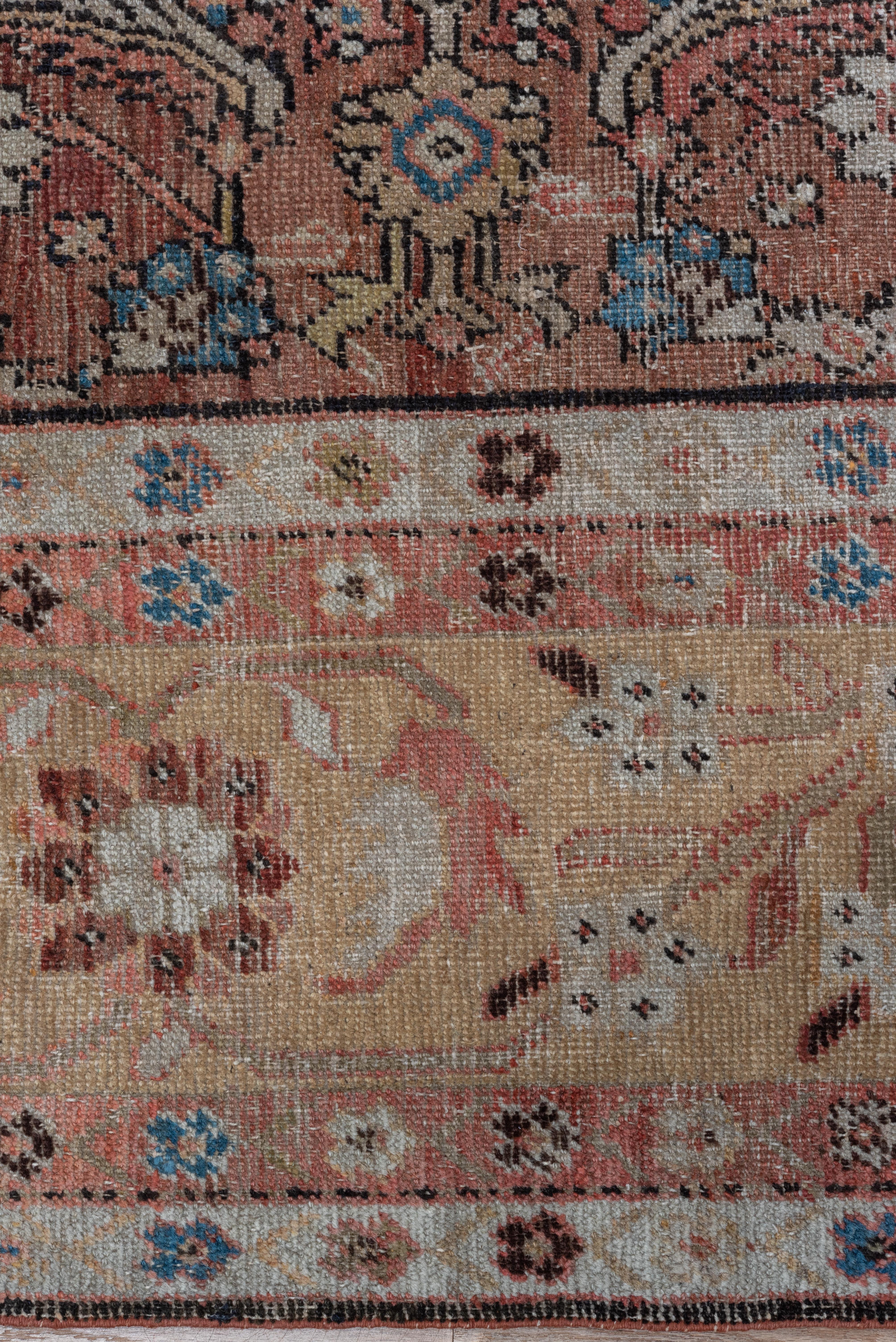 The relatively small abrashed madder red field shows a Classic Herati all-over pattern of rosettes, open lozenges and lancet leaves accented in cream, green and lighter blue. This west Persian rustic room size carpet has a particularly wide straw