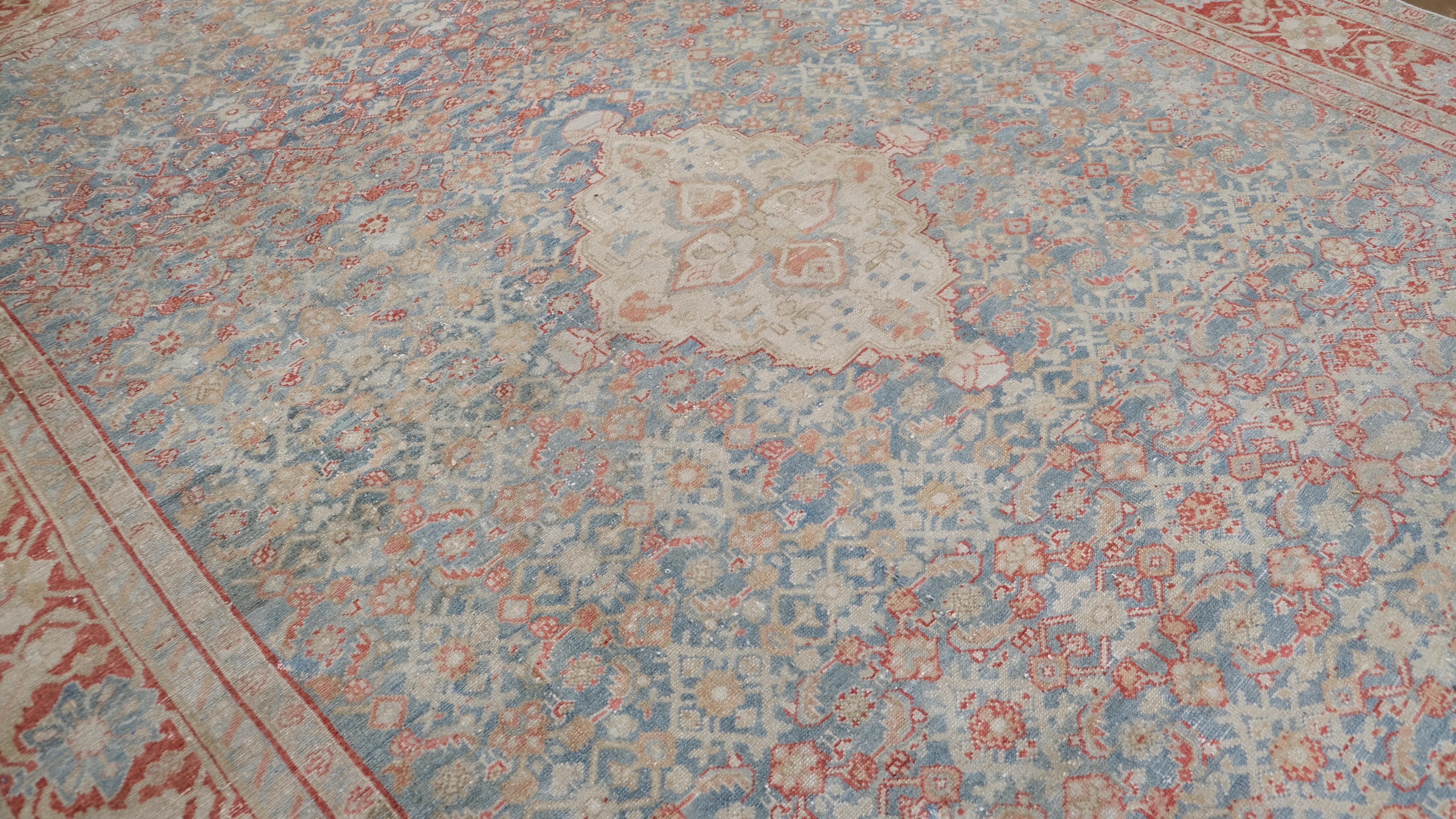 Dieser atemberaubende antike, handgeknüpfte Wollteppich zeigt ein kompliziertes, florales Allover-Muster mit einem wunderschön detaillierten Medaillon in der Mitte. Vor dem Hintergrund eines sanften blauen Feldes wird das Design durch zartes Rot und