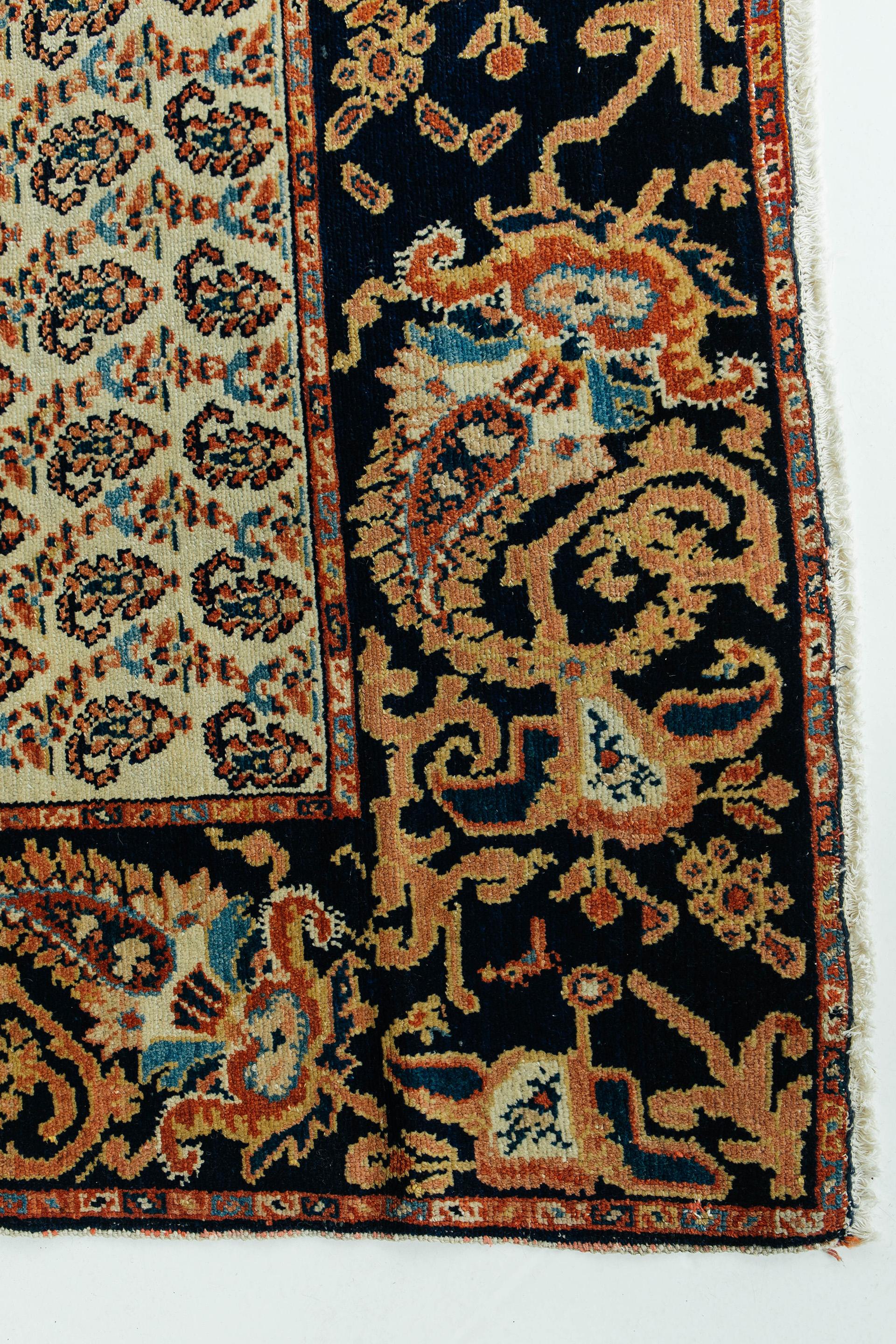 Antique Malayer with ivory field, deep indigo border, and red, pink and gold tones. This rug features an all-over repeat boteh pattern with an elaborate foliate border of large-scale boteh forms. The boteh motif is a common decorative element with