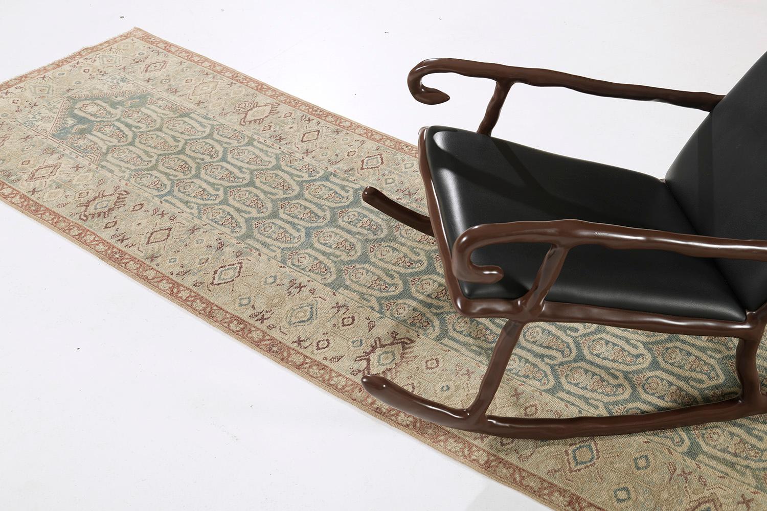 A remarkable hand-spun wool Persian Malayer Runner has immensely flexed its Bote-styled pattern along the perimeter of emblems and symbols in the teal ground. It is surrounded by different kinds of symbolic imprints in brown and gold elements. The