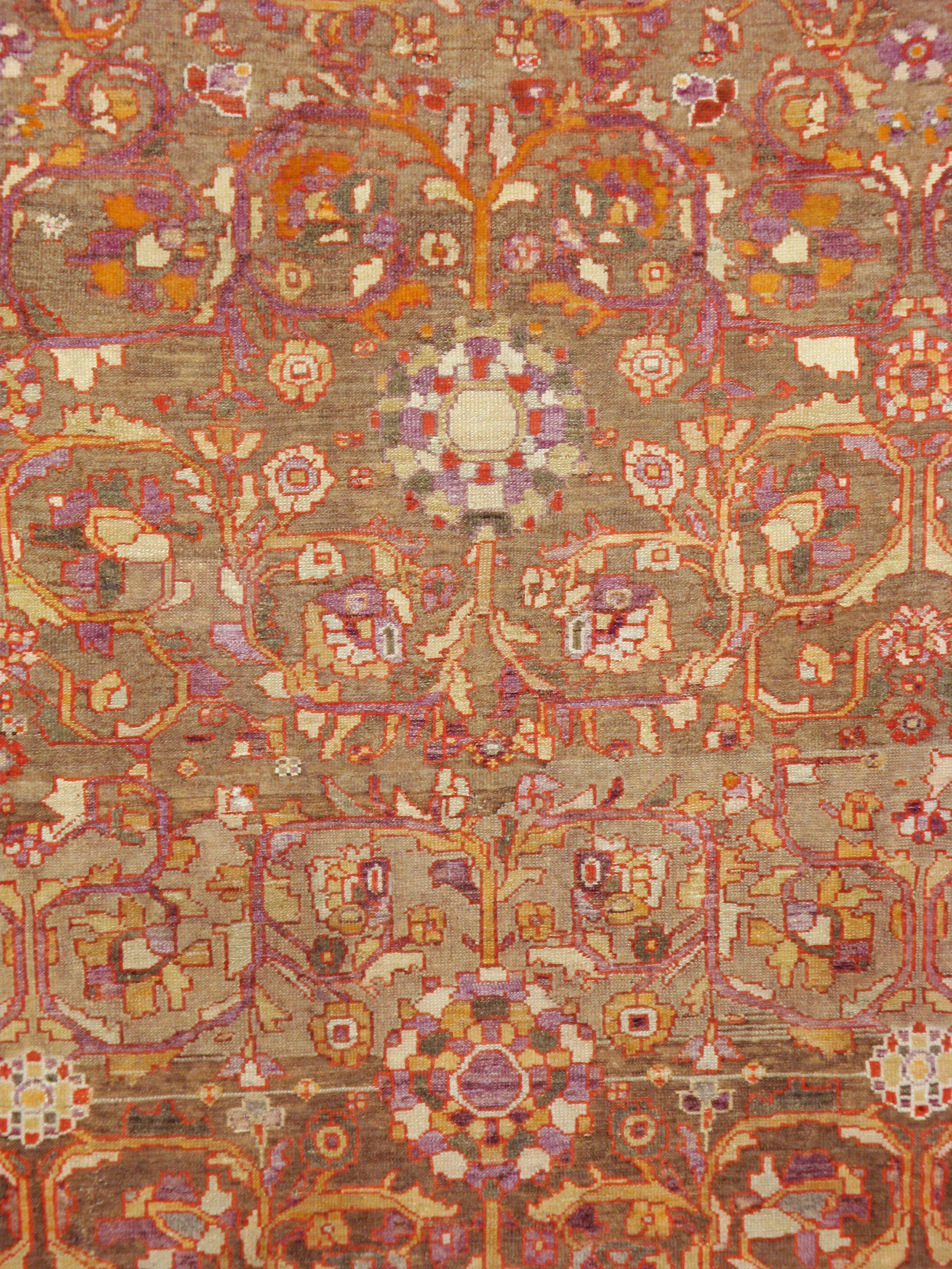 An antique Persian Malayer carpet from the early 20th century. Bichrome palmettes along the central axis of the medium brown field of this Hamadan area town rug are flanked by doubled serrated and curved leaves. An old ivory border of diamond shapes