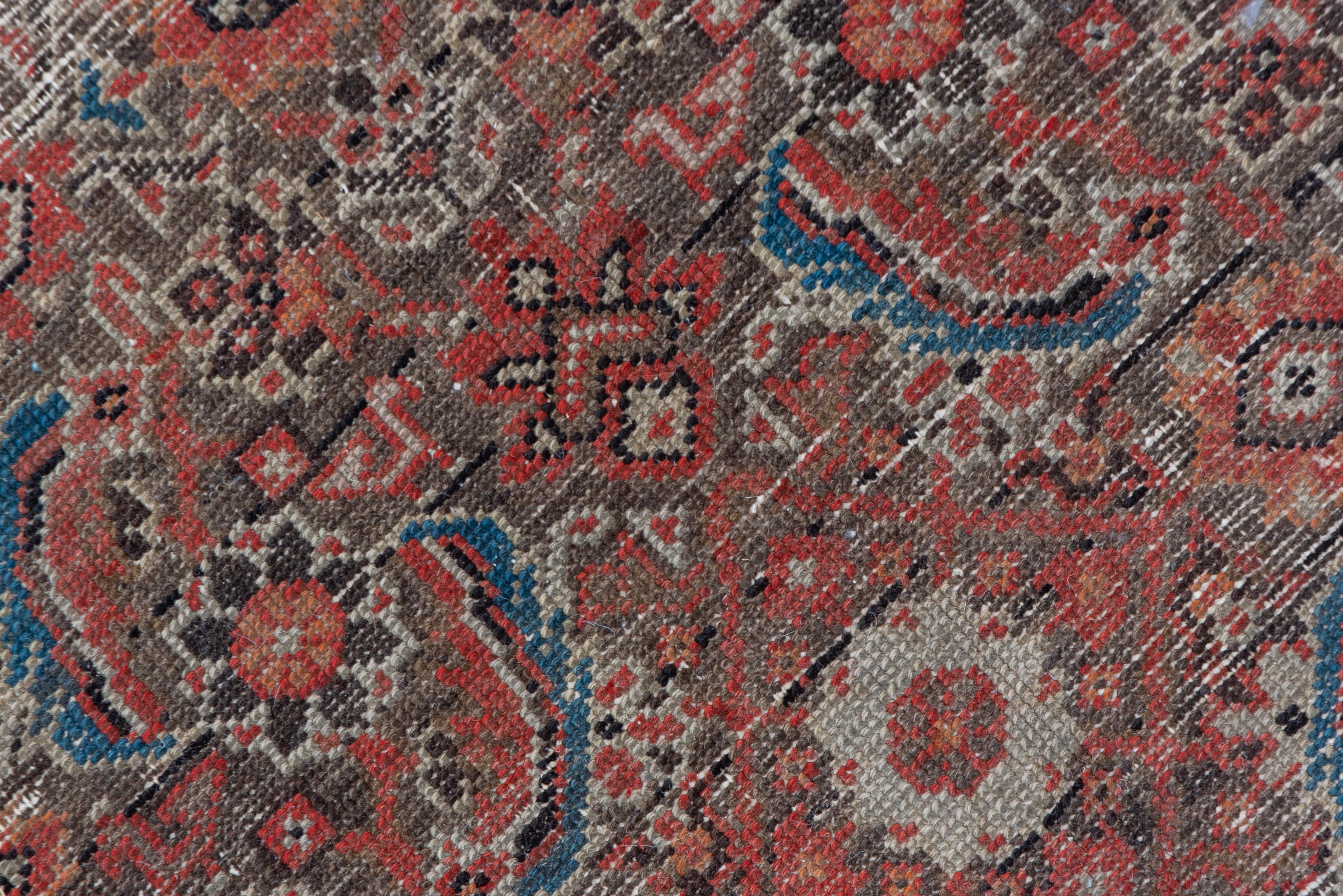 This rather distressed west Persian carpet shows an all-over Herati pattern with straw ivory rosettes amid curved 'fish' leaves and open lozenges on the muted cranberry field. The distress somewhat lightens the overall palette.
 