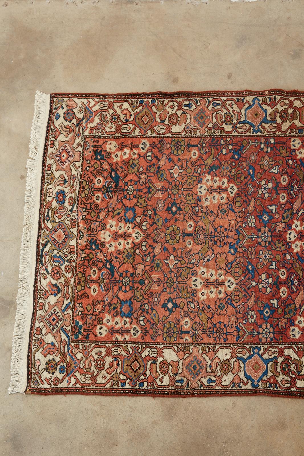 Stylish early 20th century antique Persian Malayer rug features hand knotted wool with a cotton warp. Beautiful age with abrash. The field varies different shades of jewel tone reds from pinks to garnet. Decorated with light hyacinth flowers and
