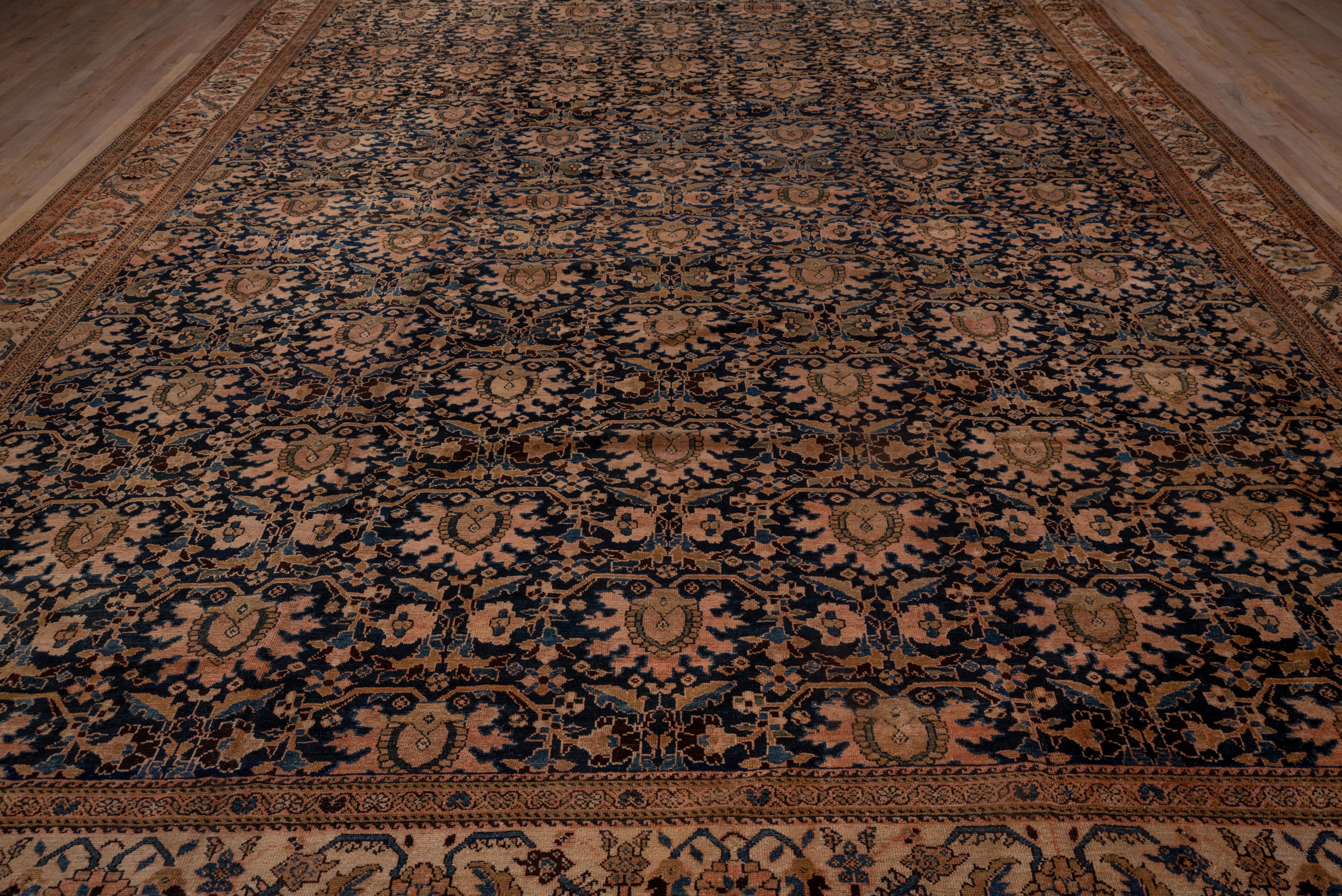 The charcoal field is covered by a one-way, offset ragged palmette pattern accented in straw, rust, dark brown and buff. The sandy straw main border of this extra-large west Persian town car pet shows a version of the tangerine flower design, but