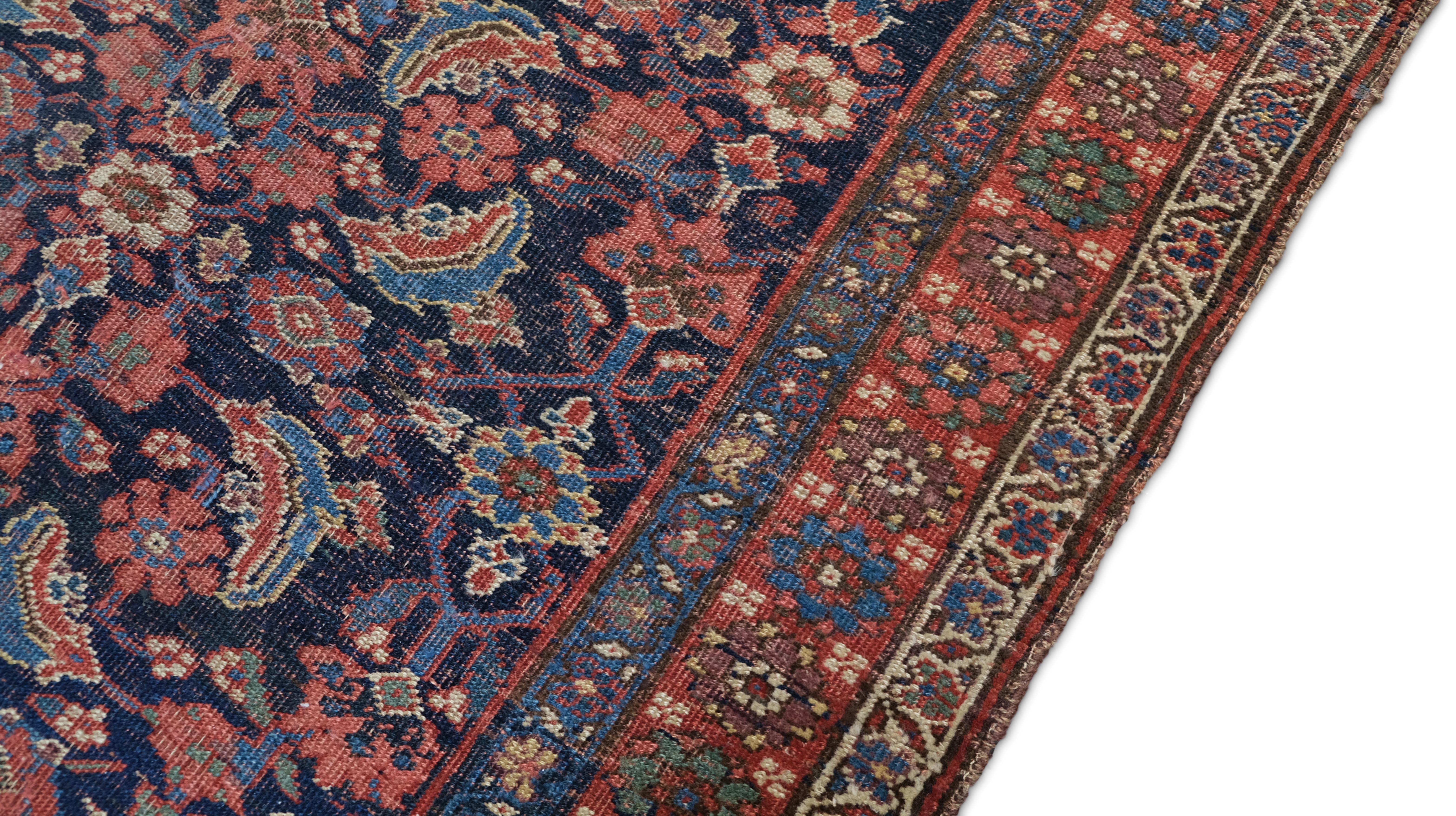 Dieser antike, handgeknüpfte Wollteppich zeigt die zeitlose Eleganz und die aufwendige Handwerkskunst der  reiche Weberei-Traditionen. Dieser Teppich mit einem detaillierten Blumenfeld mit Arabeskenmotiven wird durch einen Hintergrund in tiefem