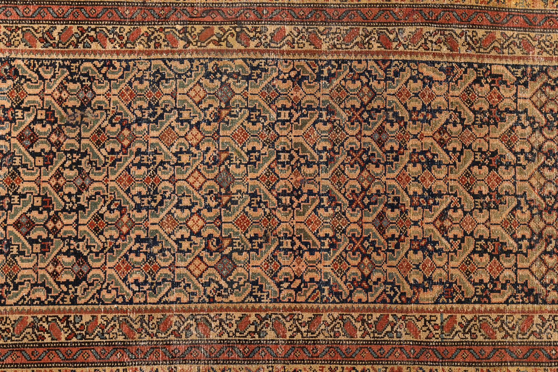 Malayer – Northwest Persia

Antique Persian Malayer rug with a stylized design covering the entire main field of the carpet in navy with a pastel colour balance in beige, green and red tones. Stylized flowers accompany the whole golden border of the