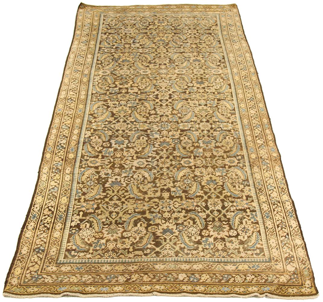 Antique Persian runner rug handwoven from the finest sheep’s wool and colored with all-natural vegetable dyes that are safe for humans and pets. It’s a traditional Malayer design featuring floral details in blue and beige over a dark brown field.