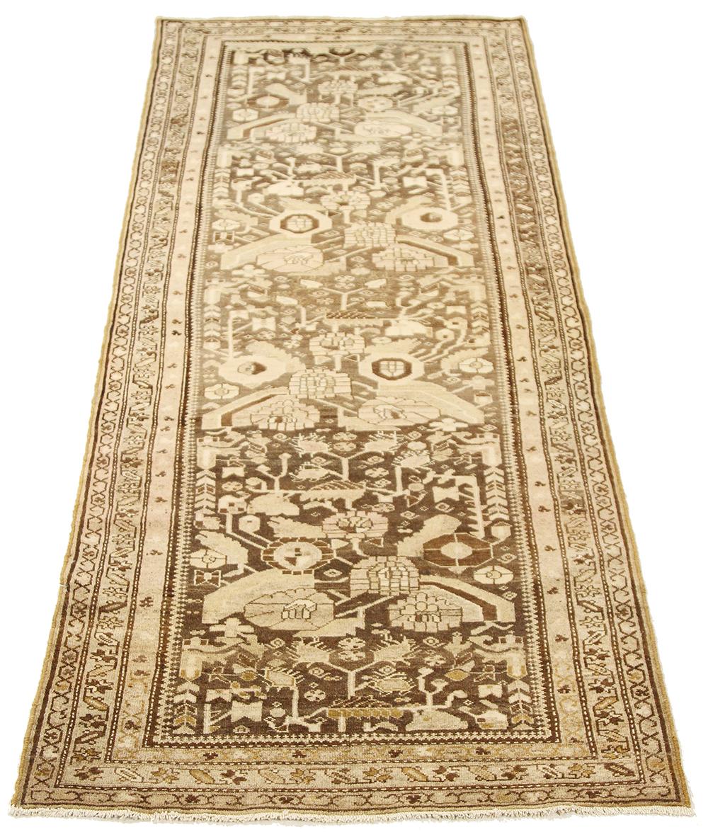 Antique Persian runner rug handwoven from the finest sheep’s wool and colored with all-natural vegetable dyes that are safe for humans and pets. It’s a traditional Malayer design featuring ivory and brown botanical details all over. It’s a lovely
