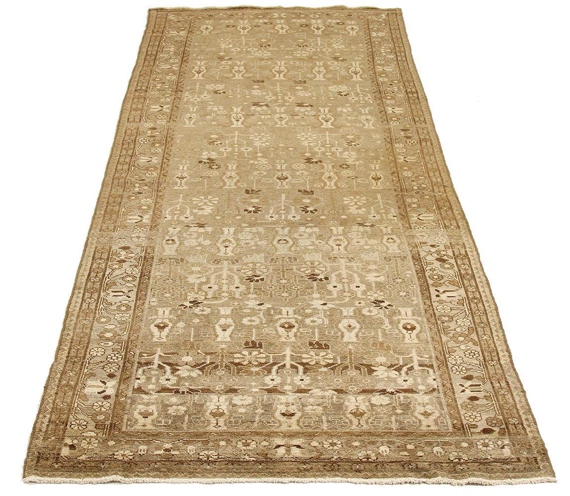 Antique Persian runner rug handwoven from the finest sheep’s wool and colored with all-natural vegetable dyes that are safe for humans and pets. It’s a traditional Malayer design featuring ivory and brown flower details all-over. It’s a lovely piece