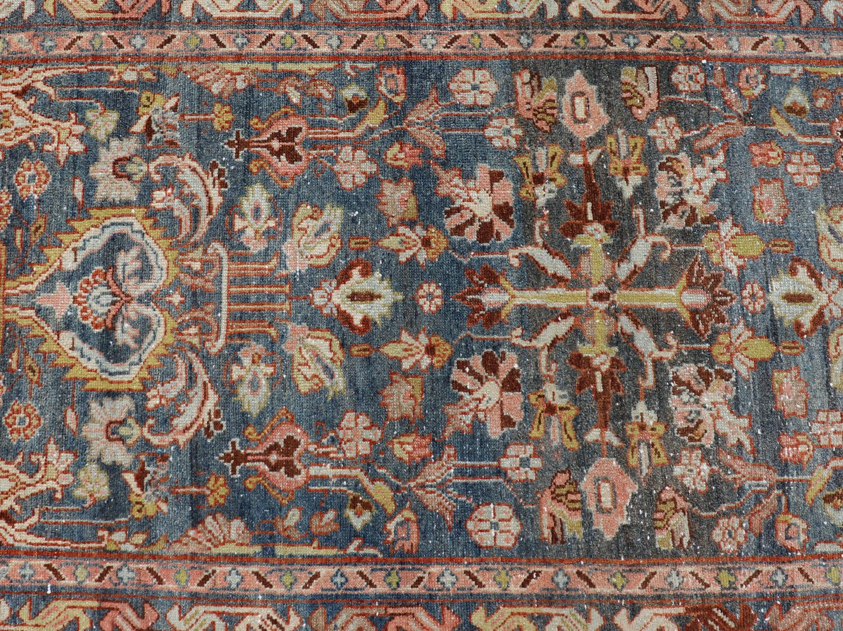 This antique Persian Malayer runner is rendered in rich colors, from the blue background to the pink, coral, light yellow, brown, and light blue shown in the design. The design is an all-over look with busy motifs spread across the entire field. The