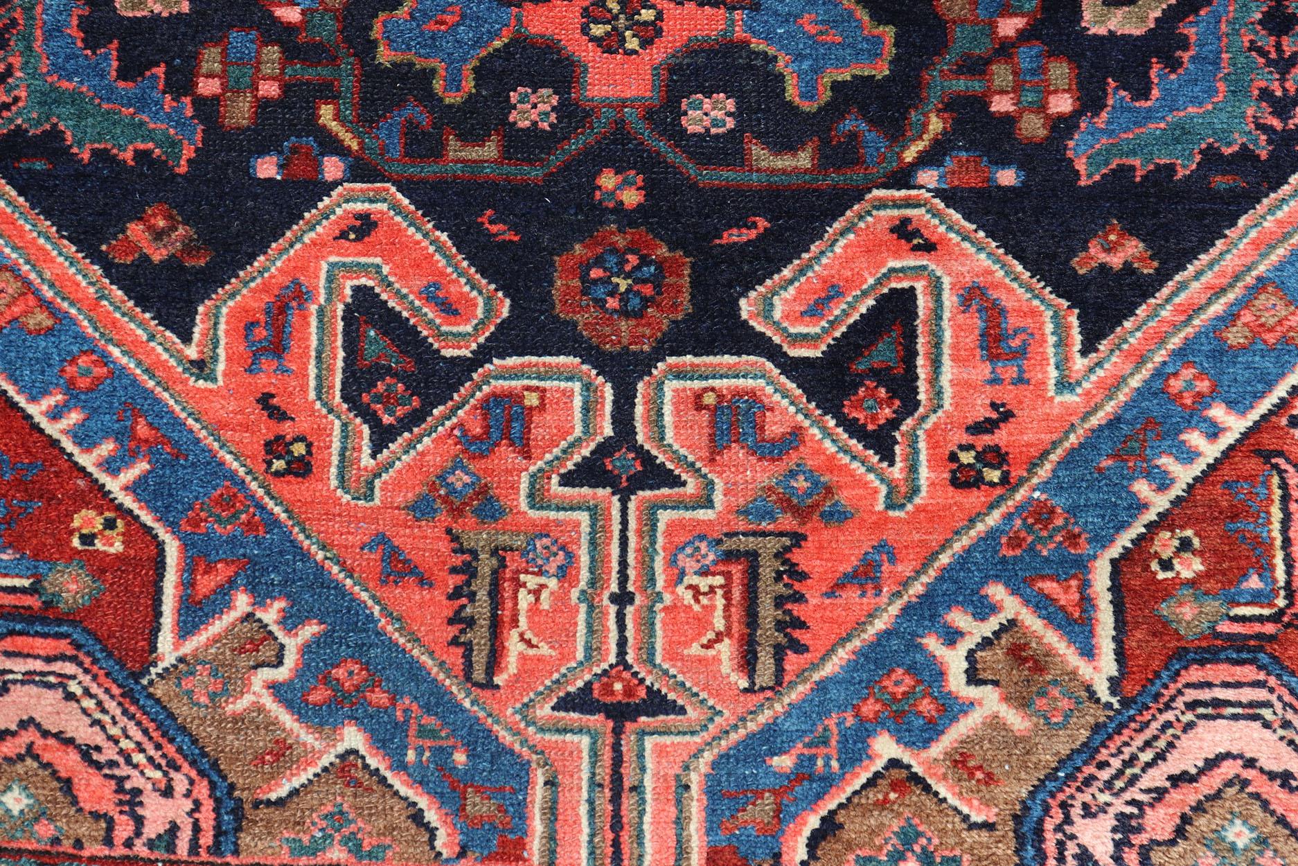 Measures: 3'5 x 16'4 

This 1930's Persian Malayer runner features vivid shades of navy, blue, red-orange, green and small accents in camel, pink, and ivory. The field design is a unique palm leaf motif design scattering across the entirety of the
