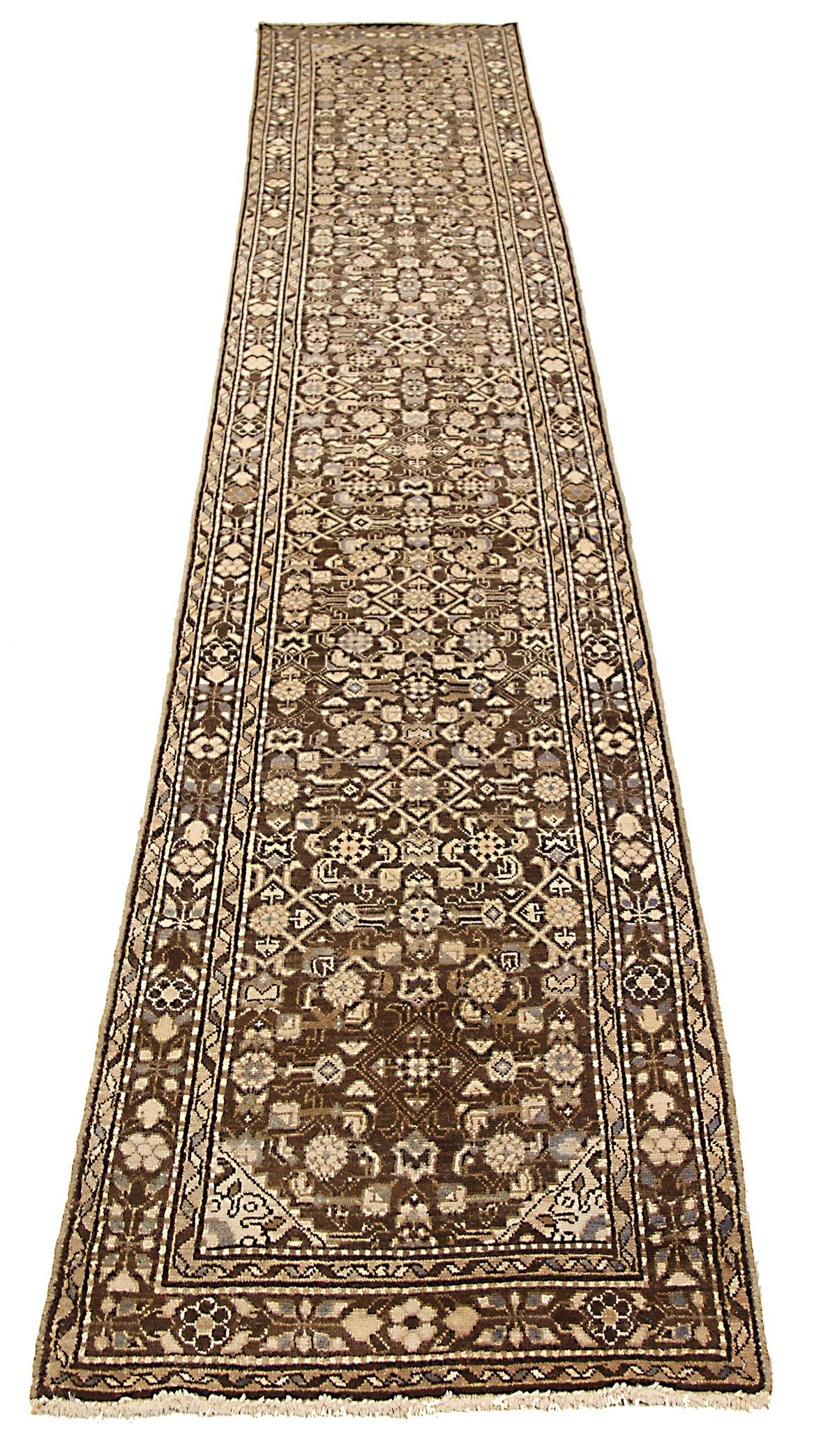 Antique Persian runner rug handwoven from the finest sheep’s wool and colored with all-natural vegetable dyes that are safe for humans and pets. It’s a traditional Malayer design featuring black and beige floral medallions over a rich brown field.