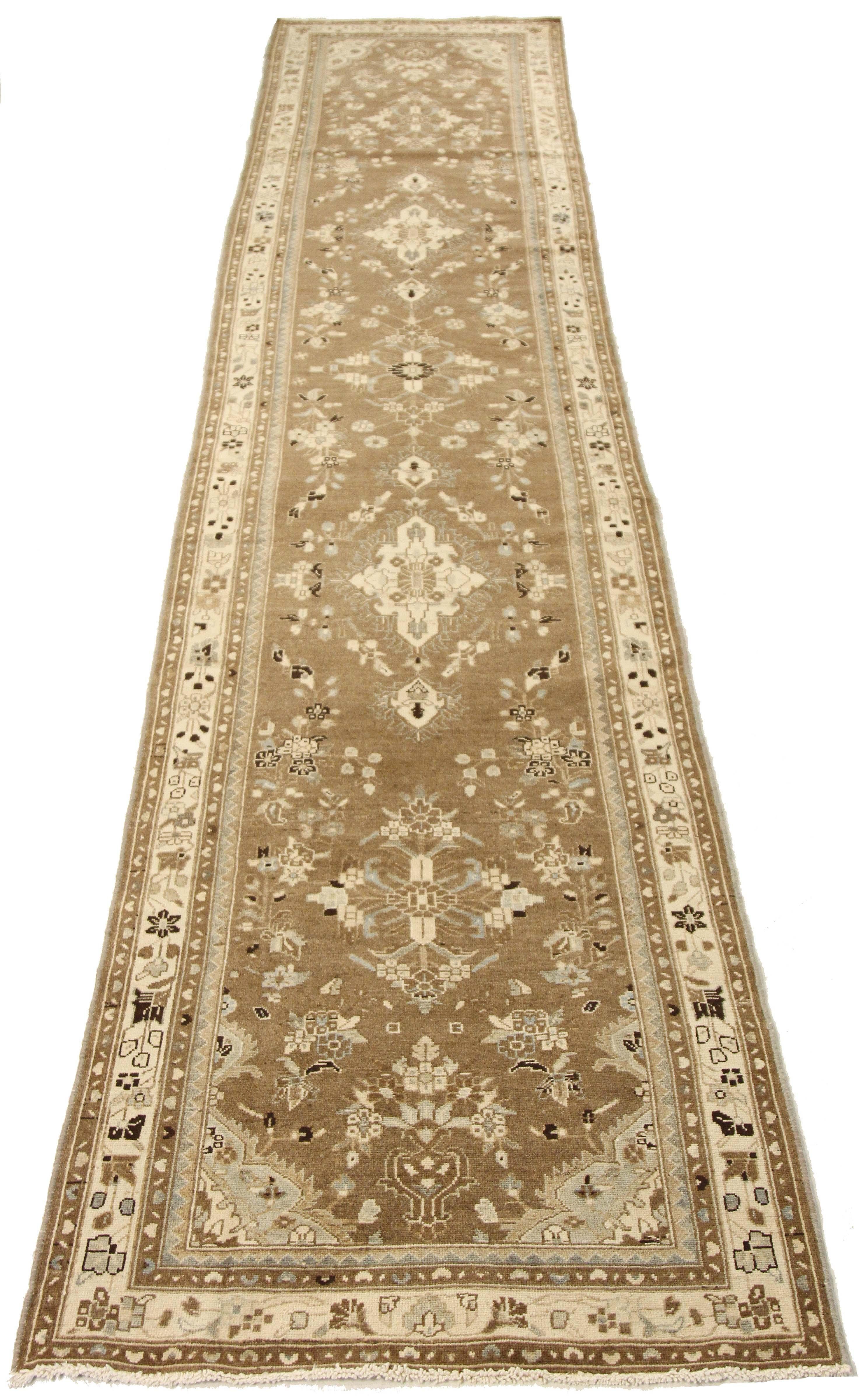 Antique Persian runner rug handwoven from the finest sheep’s wool and colored with all-natural vegetable dyes that are safe for humans and pets. It’s a traditional Malayer design featuring black and ivory floral patterns over a brown field. It’s a