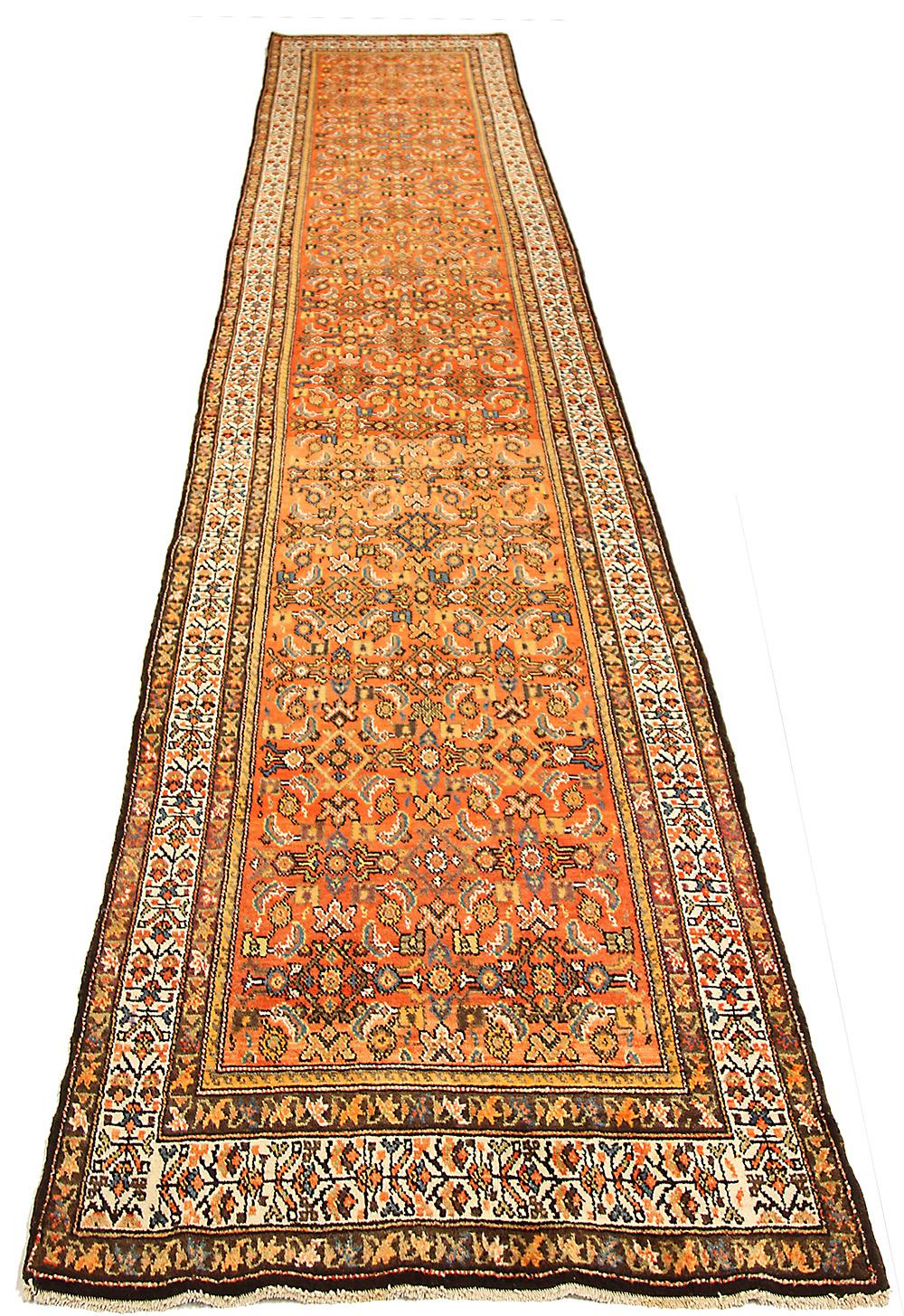 Antique Persian runner rug handwoven from the finest sheep’s wool and colored with all-natural vegetable dyes that are safe for humans and pets. It’s a traditional Malayer design featuring blue and white floral details on an orange and red field.