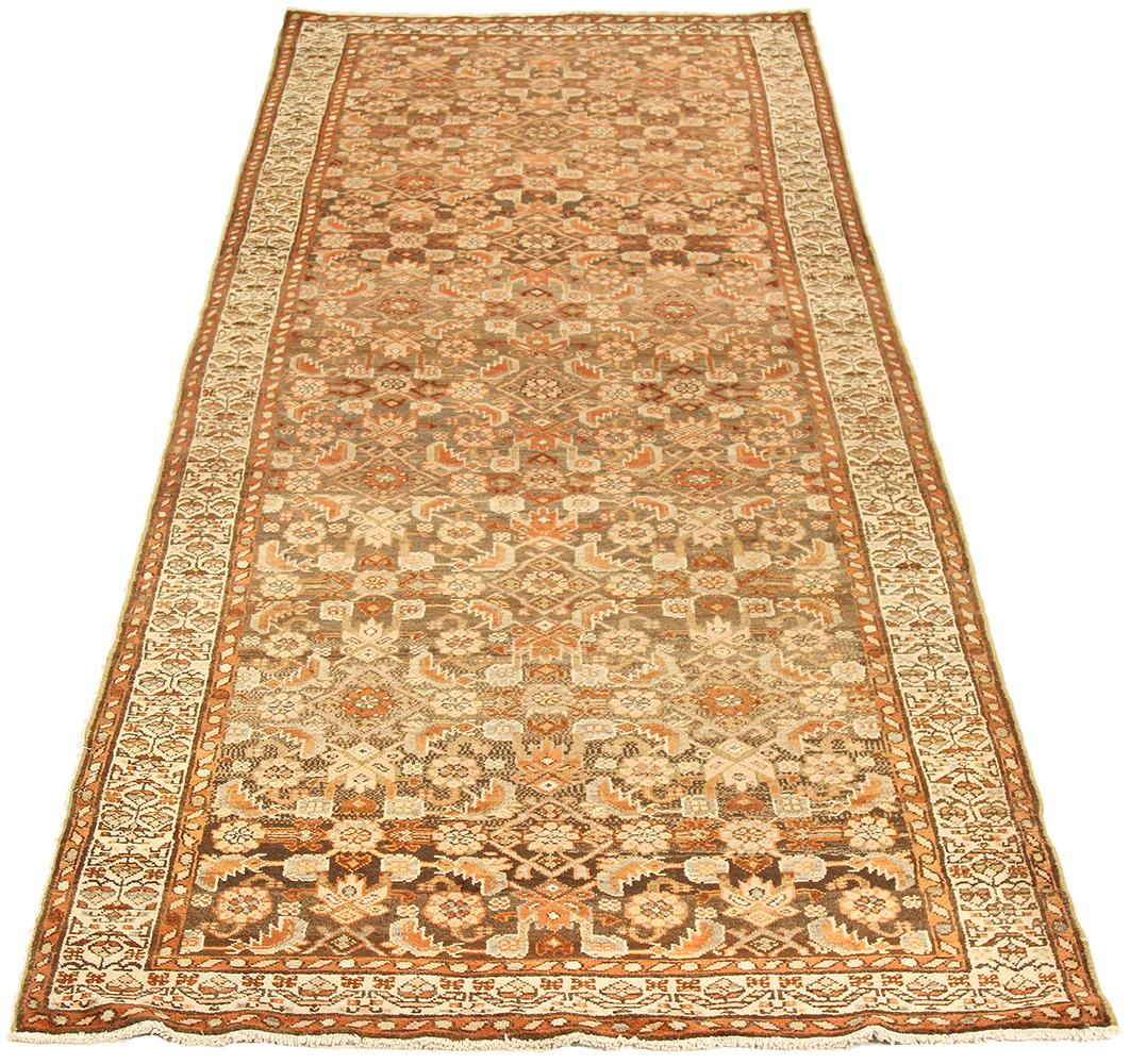 Antique Persian runner rug handwoven from the finest sheep’s wool and colored with all-natural vegetable dyes that are safe for humans and pets. It’s a traditional Malayer design featuring brown and beige flower heads all-over. It’s a lovely piece