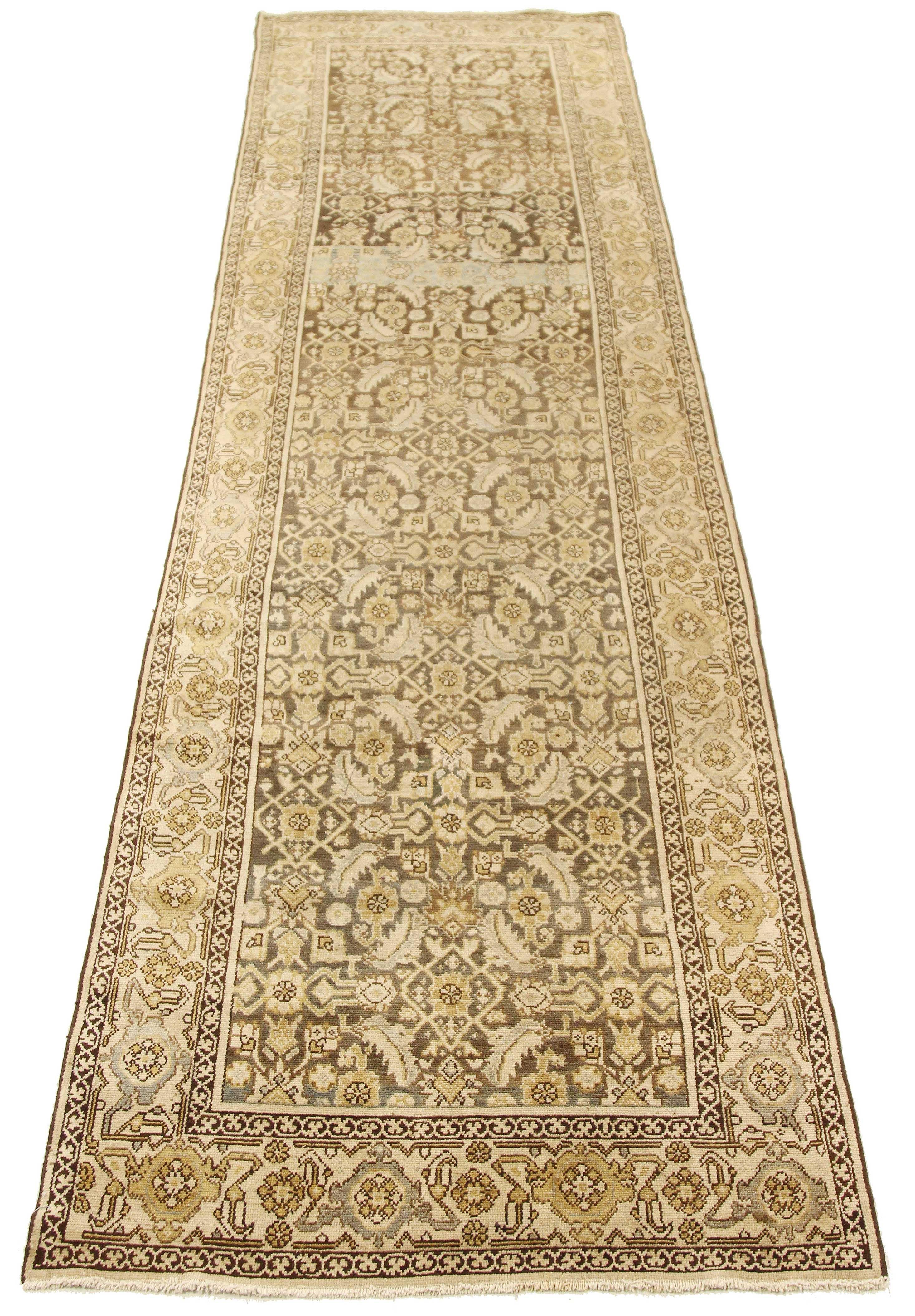 Antique Persian runner rug handwoven from the finest sheep’s wool and colored with all-natural vegetable dyes that are safe for humans and pets. It’s a traditional Malayer design featuring gray and beige botanical details on a brown and ivory field.
