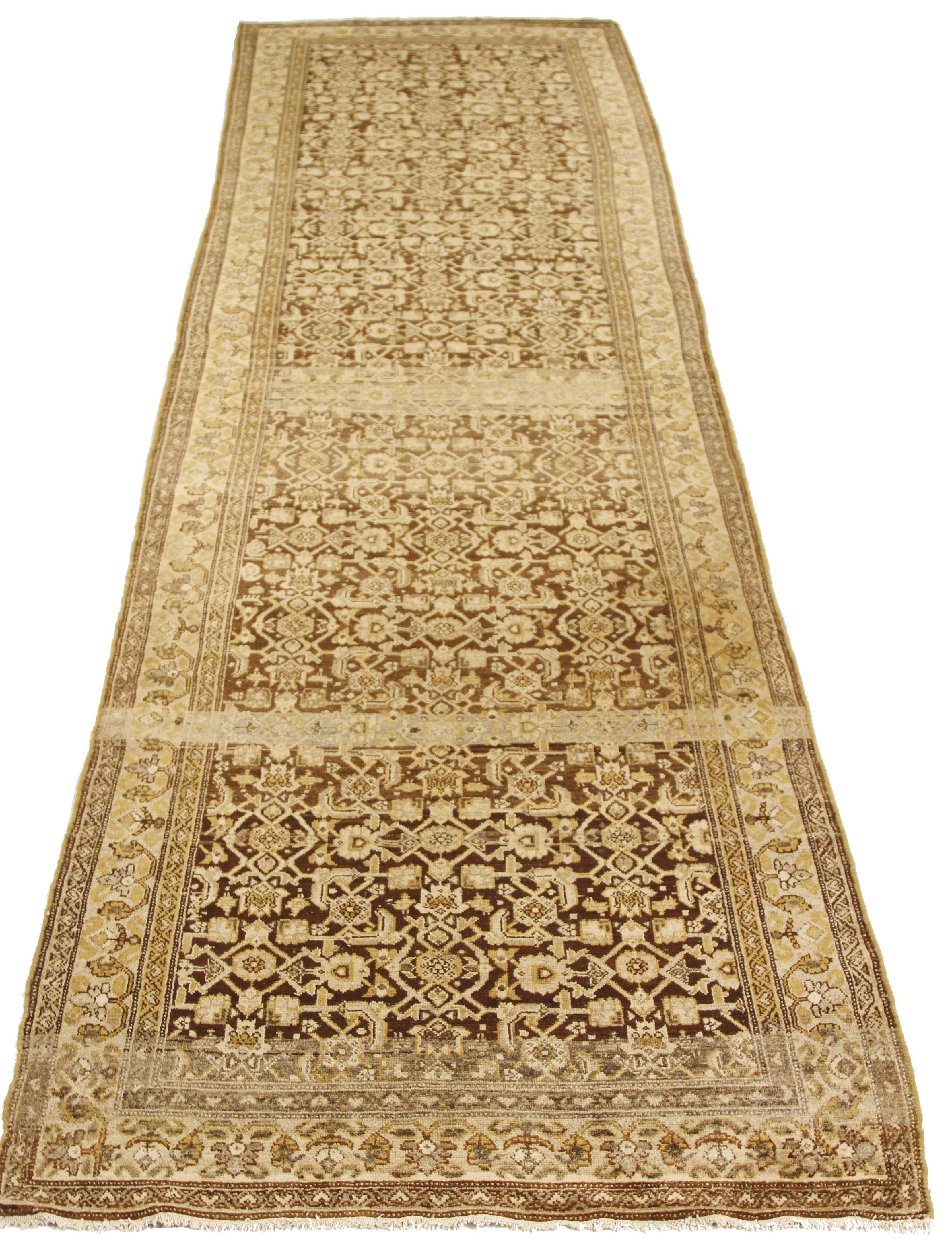 Antique Persian runner rug handwoven from the finest sheep’s wool and colored with all-natural vegetable dyes that are safe for humans and pets. It’s a traditional Malayer design featuring ivory and beige over a brown field. It’s a lovely piece to