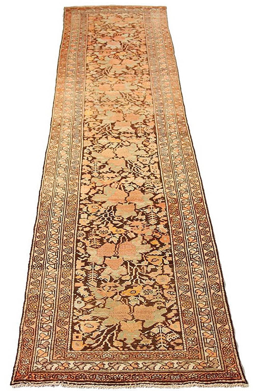 Antique Persian runner rug handwoven from the finest sheep’s wool and colored with all-natural vegetable dyes that are safe for humans and pets. It’s a traditional Malayer design featuring ivory and pink flower details over a brown field. It’s a