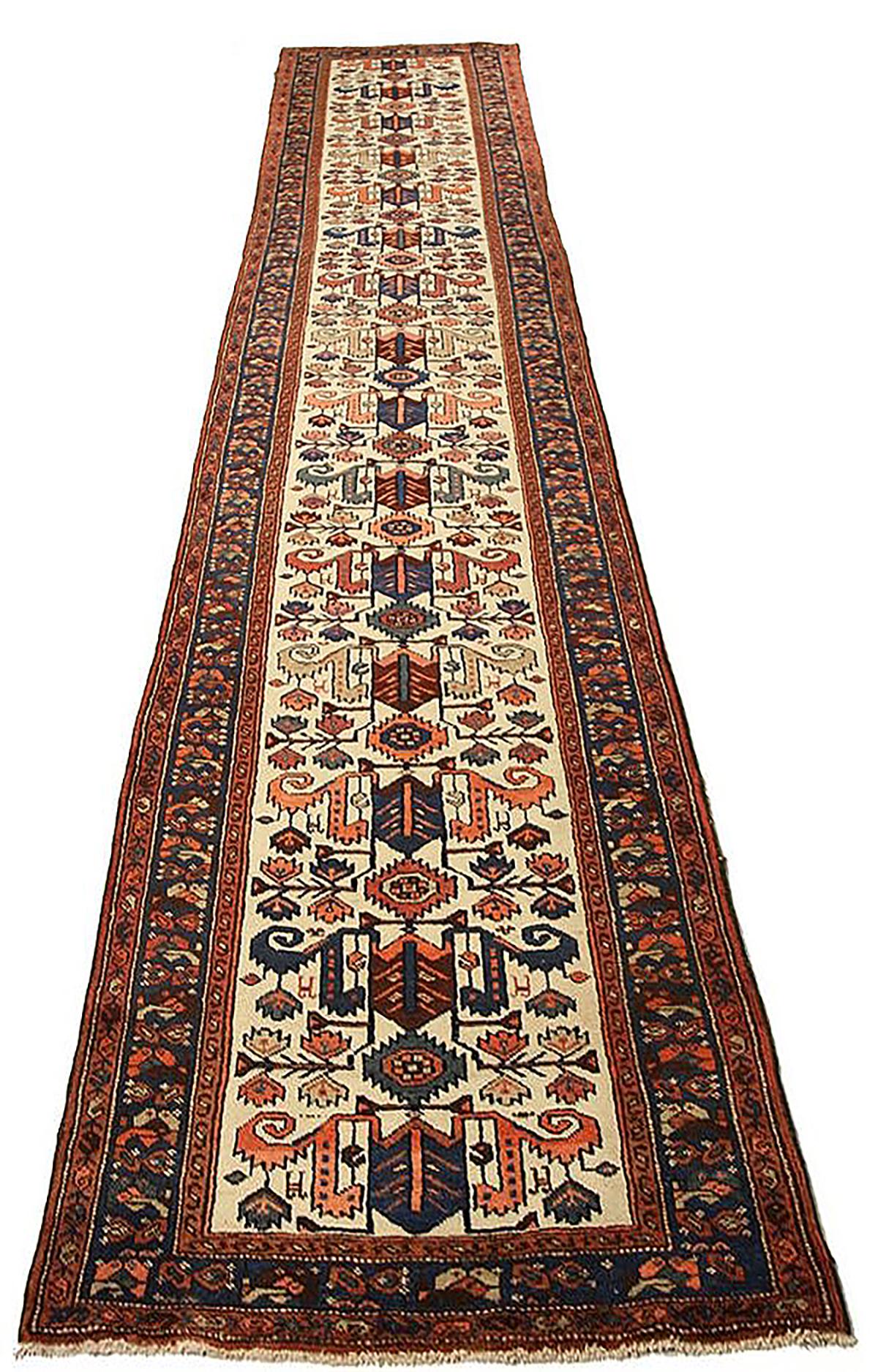 Antique Persian runner rug handwoven from the finest sheep’s wool and colored with all-natural vegetable dyes that are safe for humans and pets. It’s a traditional Malayer design featuring a mixed navy, green, and red combination of floral and