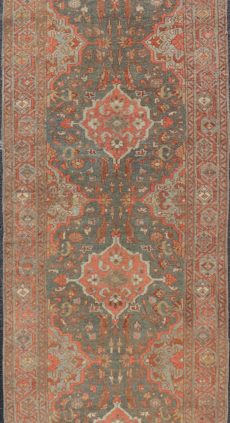 Measures: 2'10 x 9'6 

This Persian Malayer features stylized floral medallions contrasting bold colors with dark charcoal and bright red-orange, as well as soft light gray-blues and olives and cream for accents against the bold palette. The entire