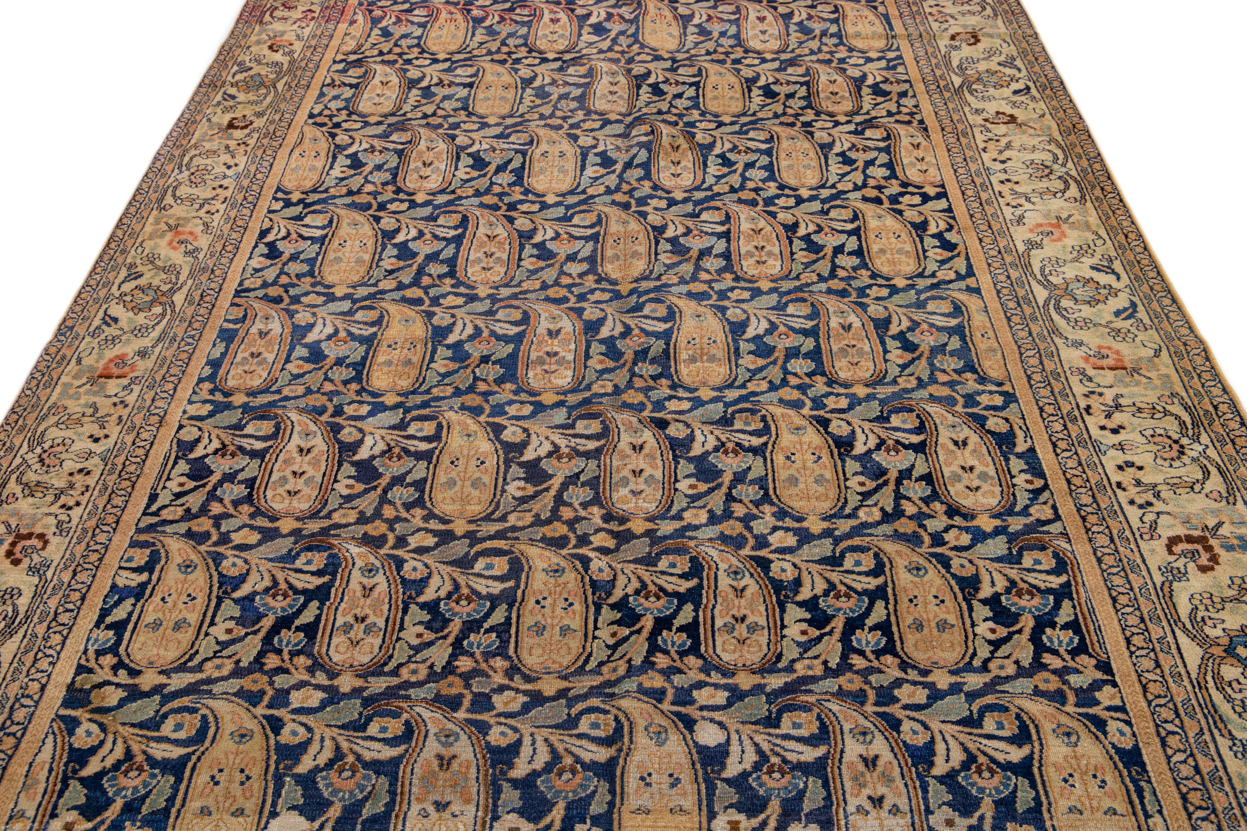 This Persian wool rug showcases a stunning hand knotted antique Mashad design. Its blue field sets the backdrop for the beautiful all-over rosette motif, framed elegantly in beige and accented with shades of brown and peach.

This rug measures