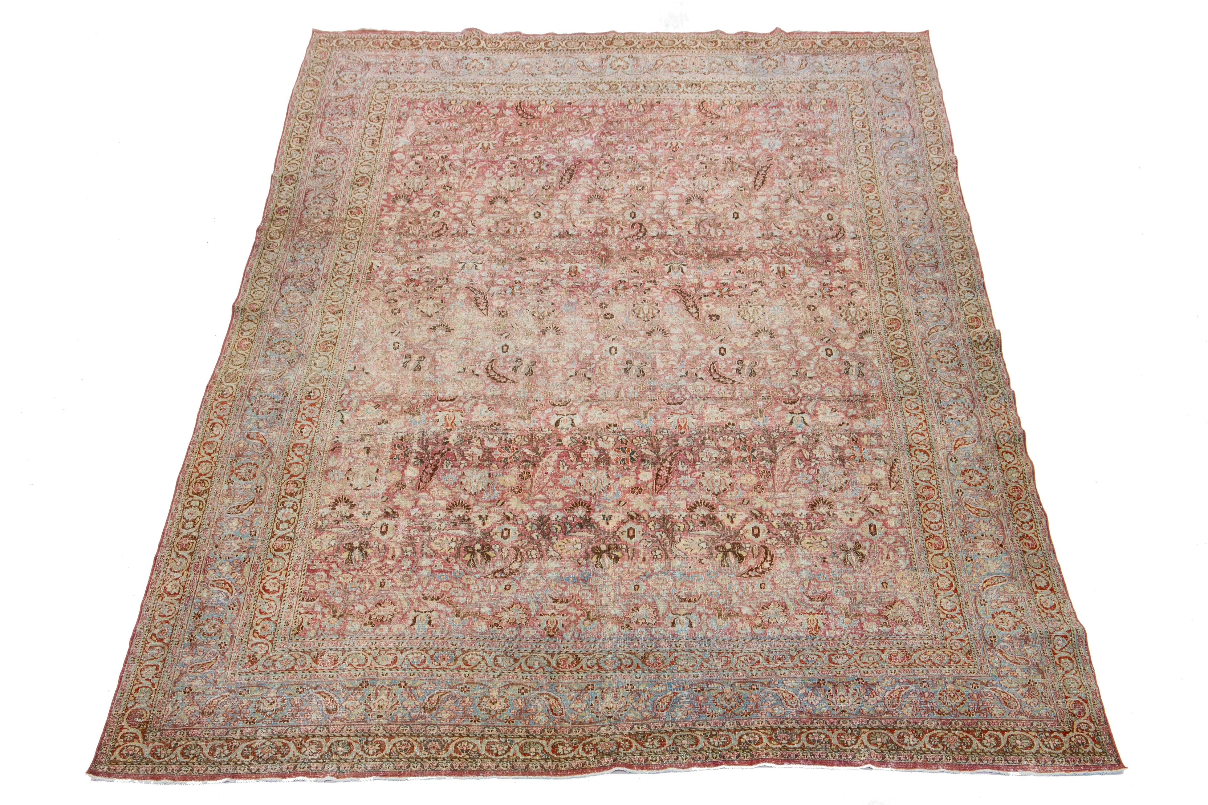 Beautiful Antique Mashad hand-knotted wool rug with a red color field. This Persian rug has a blue frame with multicolor accents in a gorgeous, classic floral design. 

This rug measures 9'9