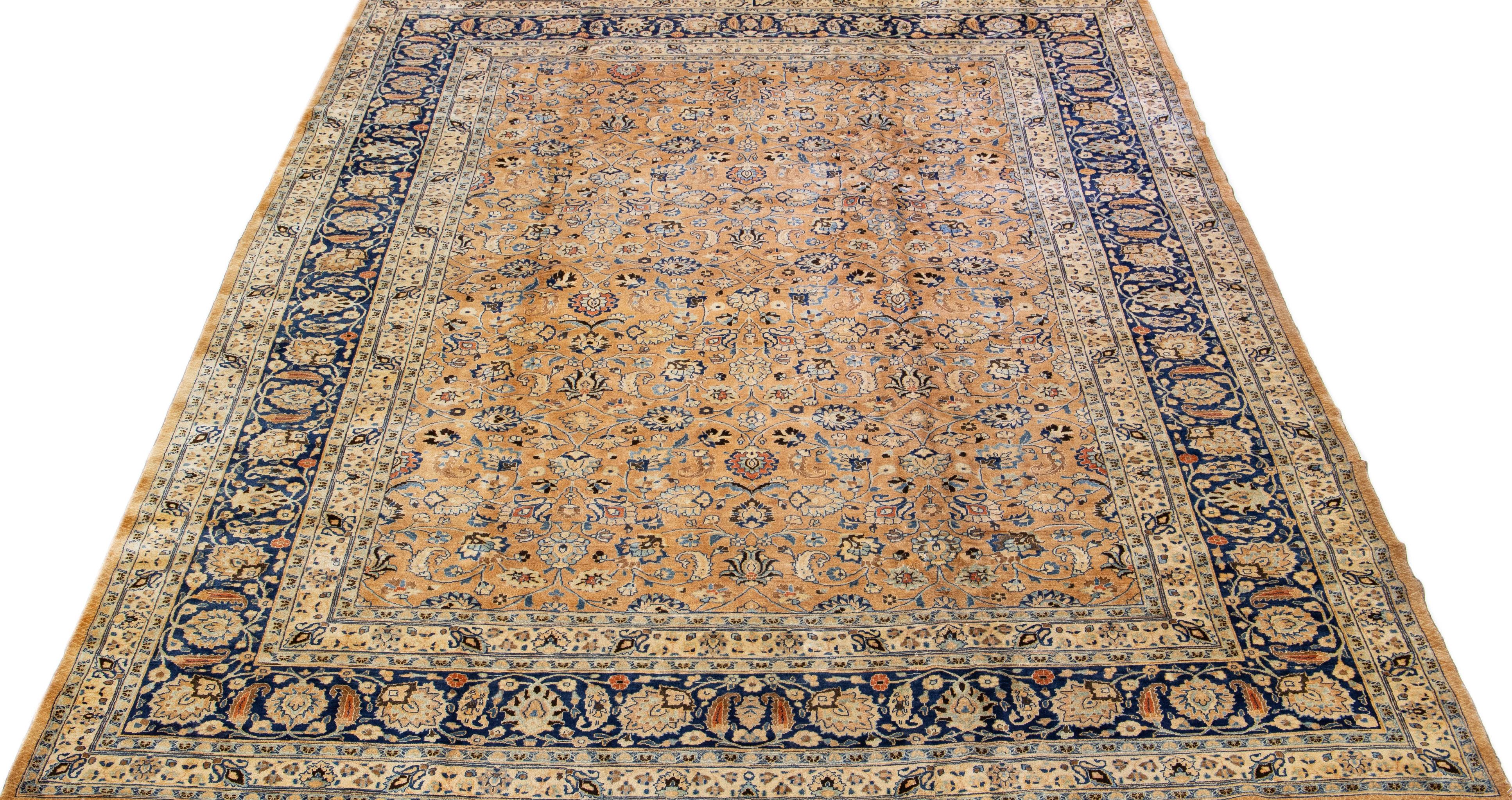 Beautiful Antique Mashad hand-knotted wool rug with a tan color field. This Persian rug has a blue designed frame with accents in a gorgeous classic floral design. 

This rug measures: 10'6