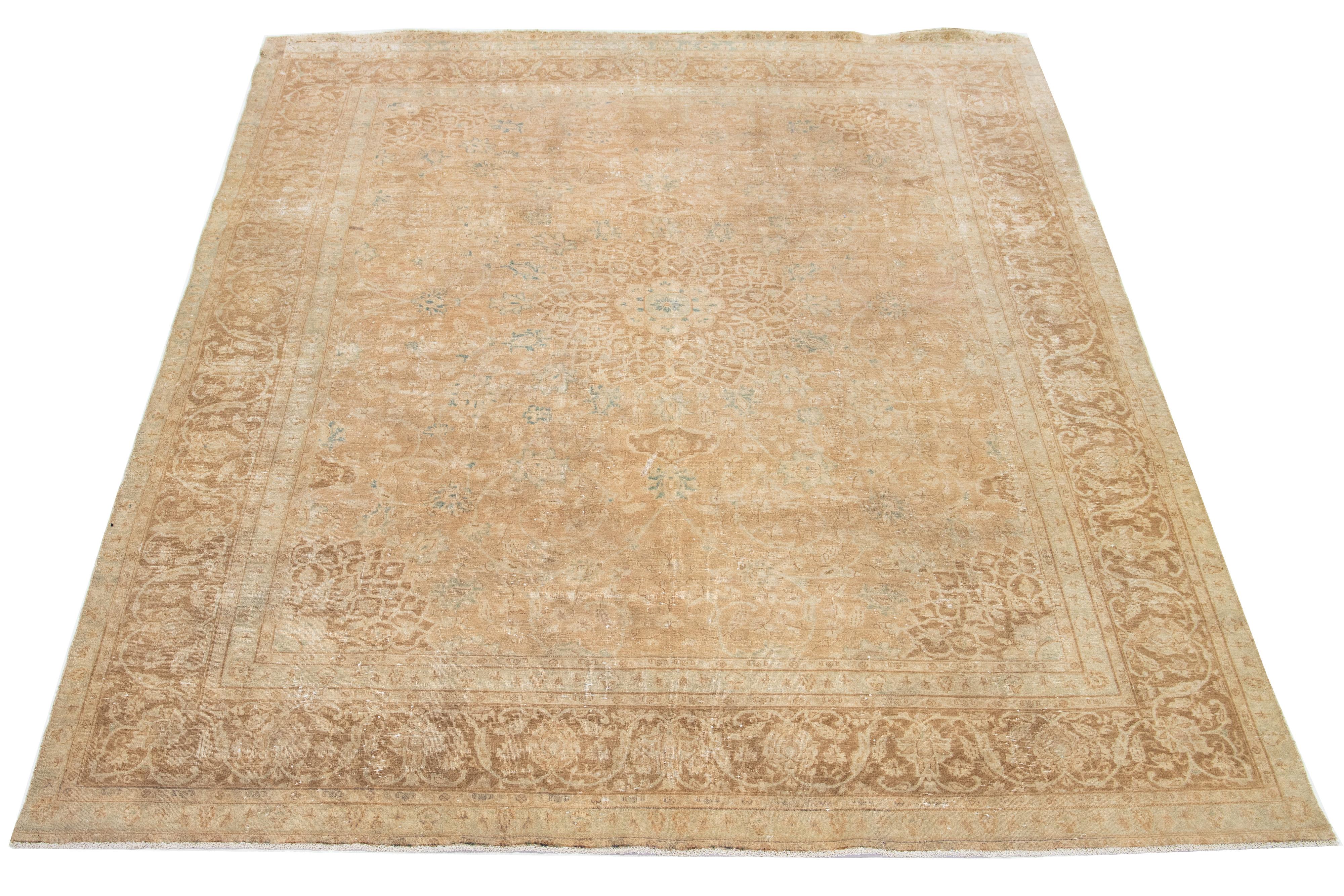  This Persian wool rug features a tan color field with blue accents in a classic rosette design. 

This rug measures 8'11