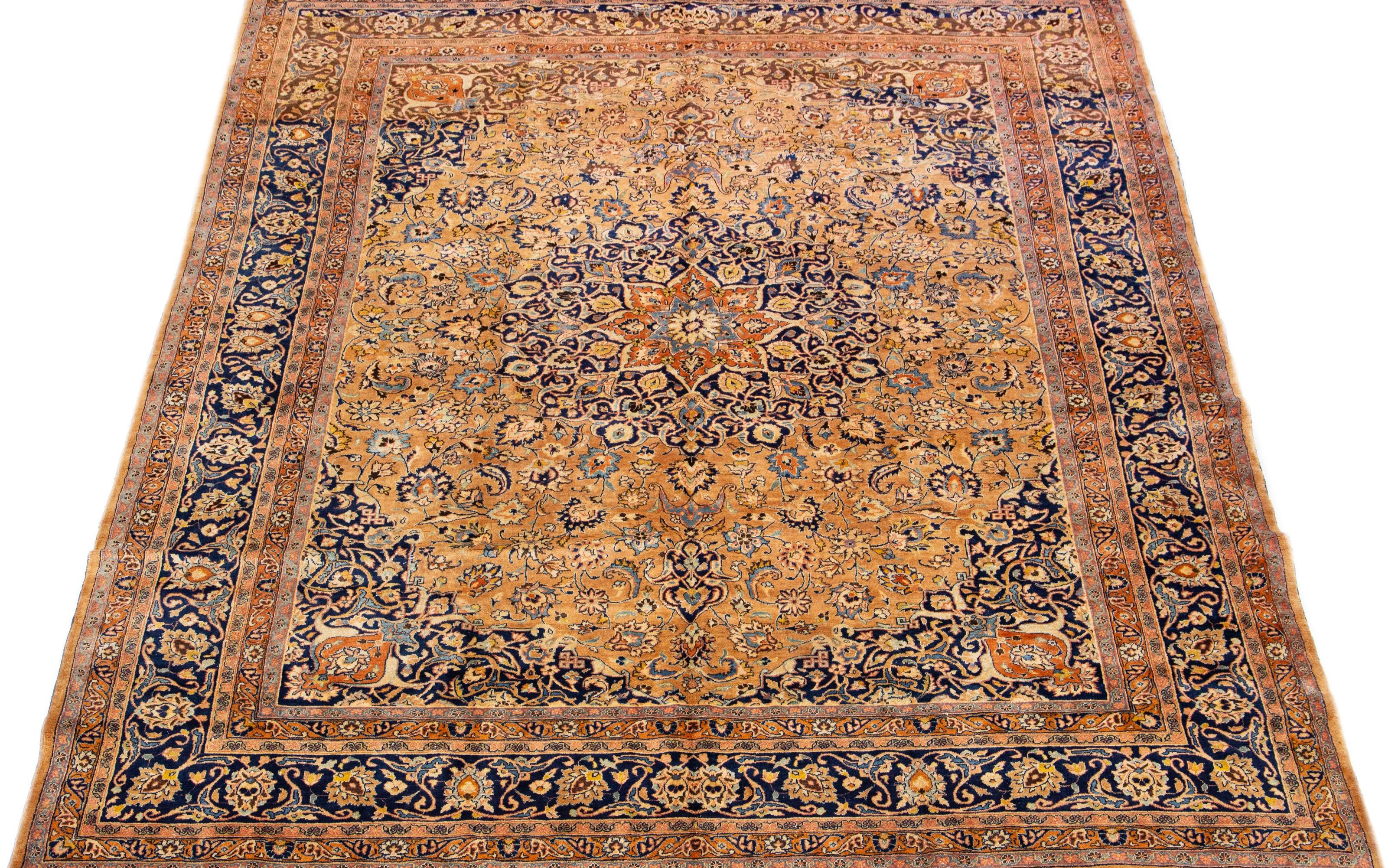 This wool rug boasts an exquisite antique Mashad hand-knotted texture, featuring a deep light brown field with an intricate blue classic medallion floral design. 

This rug measures 10'3