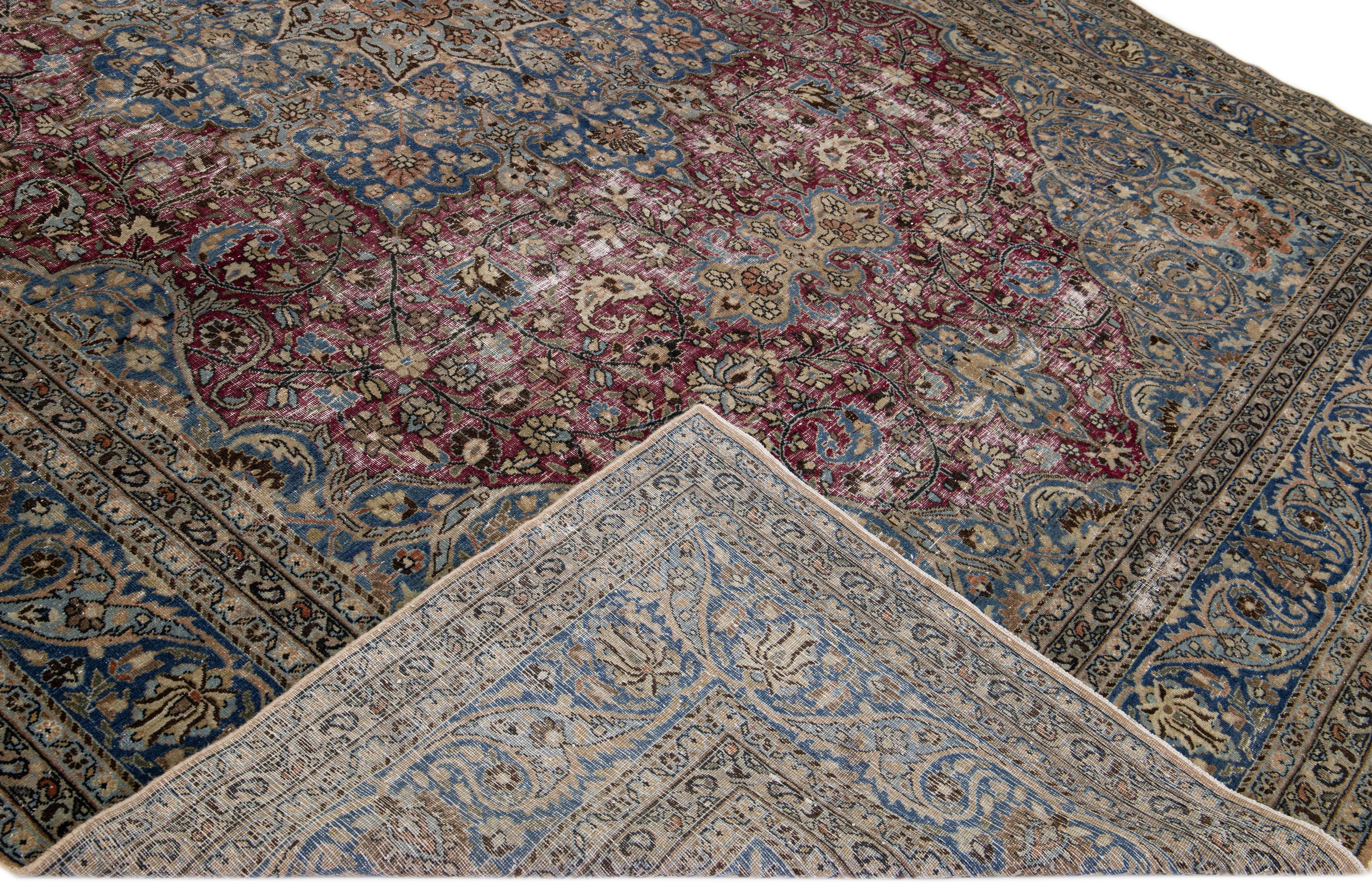 Magnifique tapis ancien de Mashad en laine nouée à la main avec un champ rouge. Ce tapis est doté d'un cadre bleu et d'un magnifique motif floral classique en médaillon. 

Ce tapis mesure : 10'7