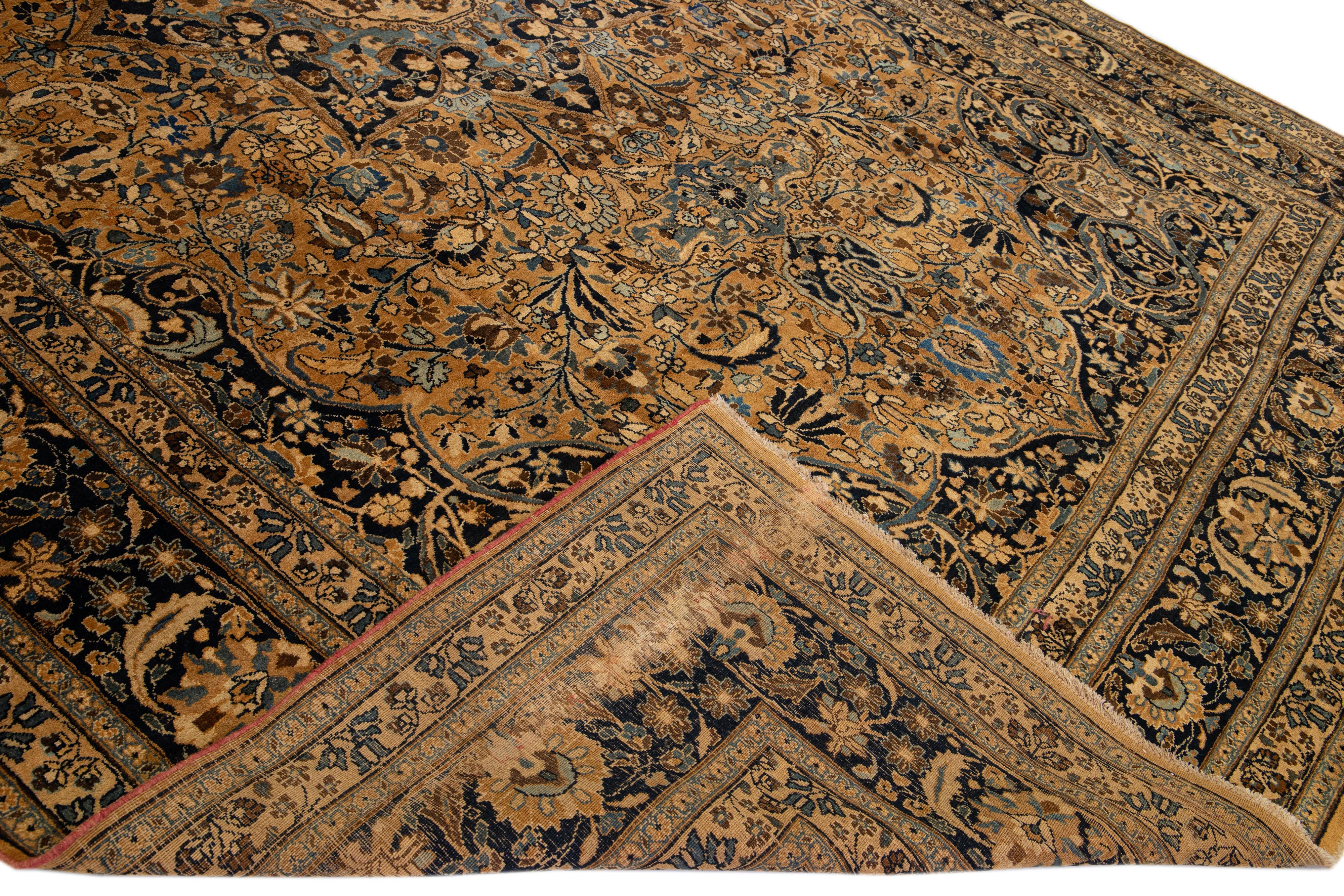 Beautiful Antique Mashad hand-knotted wool rug with a tan field. This piece rug has a blue frame and accents in a gorgeous all-over classic floral pattern design. 

This rug measures: 11' x 16'3