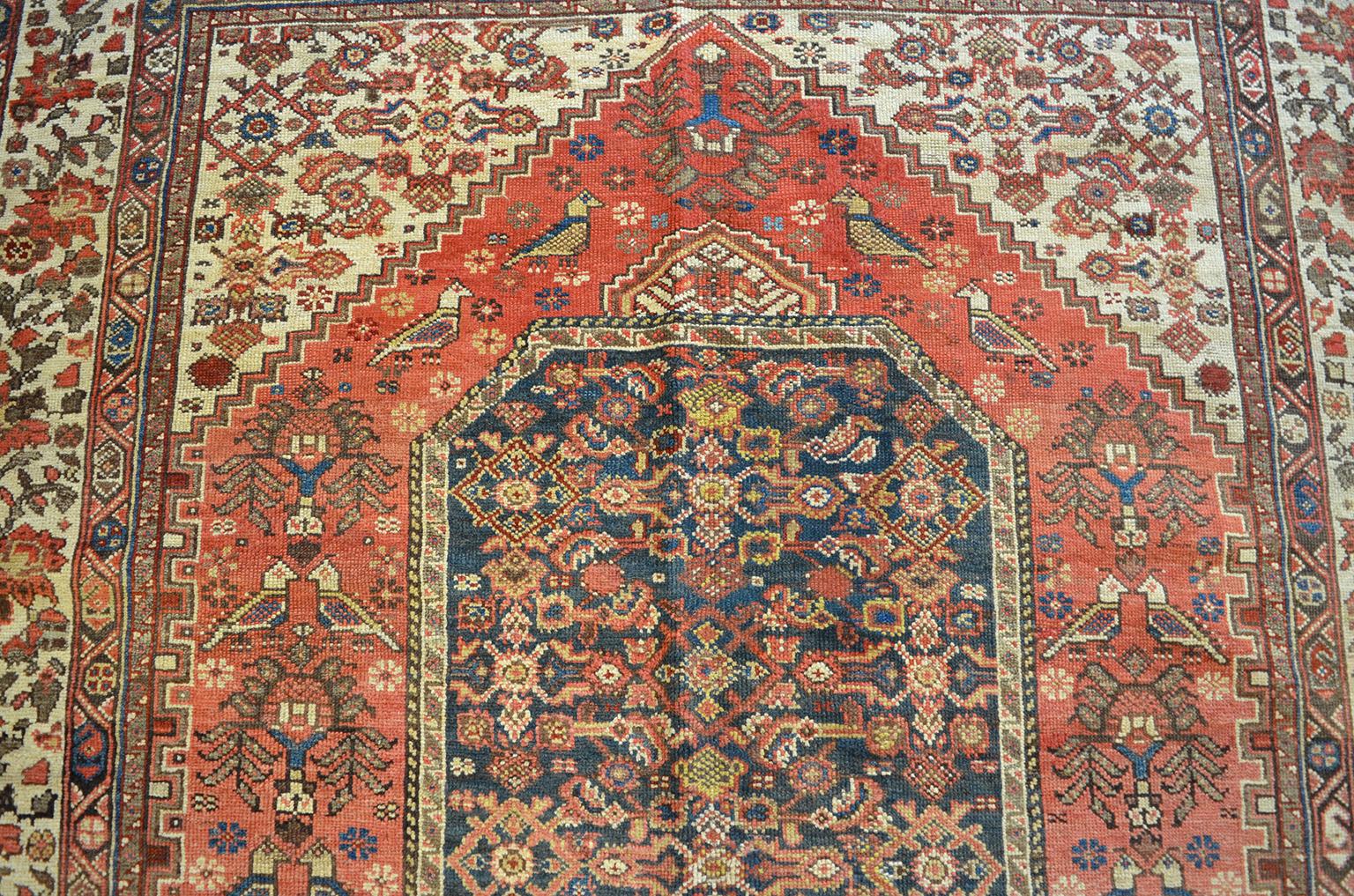 This antique Persian Meeshan Malayer carpet circa 1880 in pure handspun wool and organic vegetable dyes showcases a geometric central medallion design decorated with native birds, flowers and leaves among other symbolic tribal motifs. Completed in