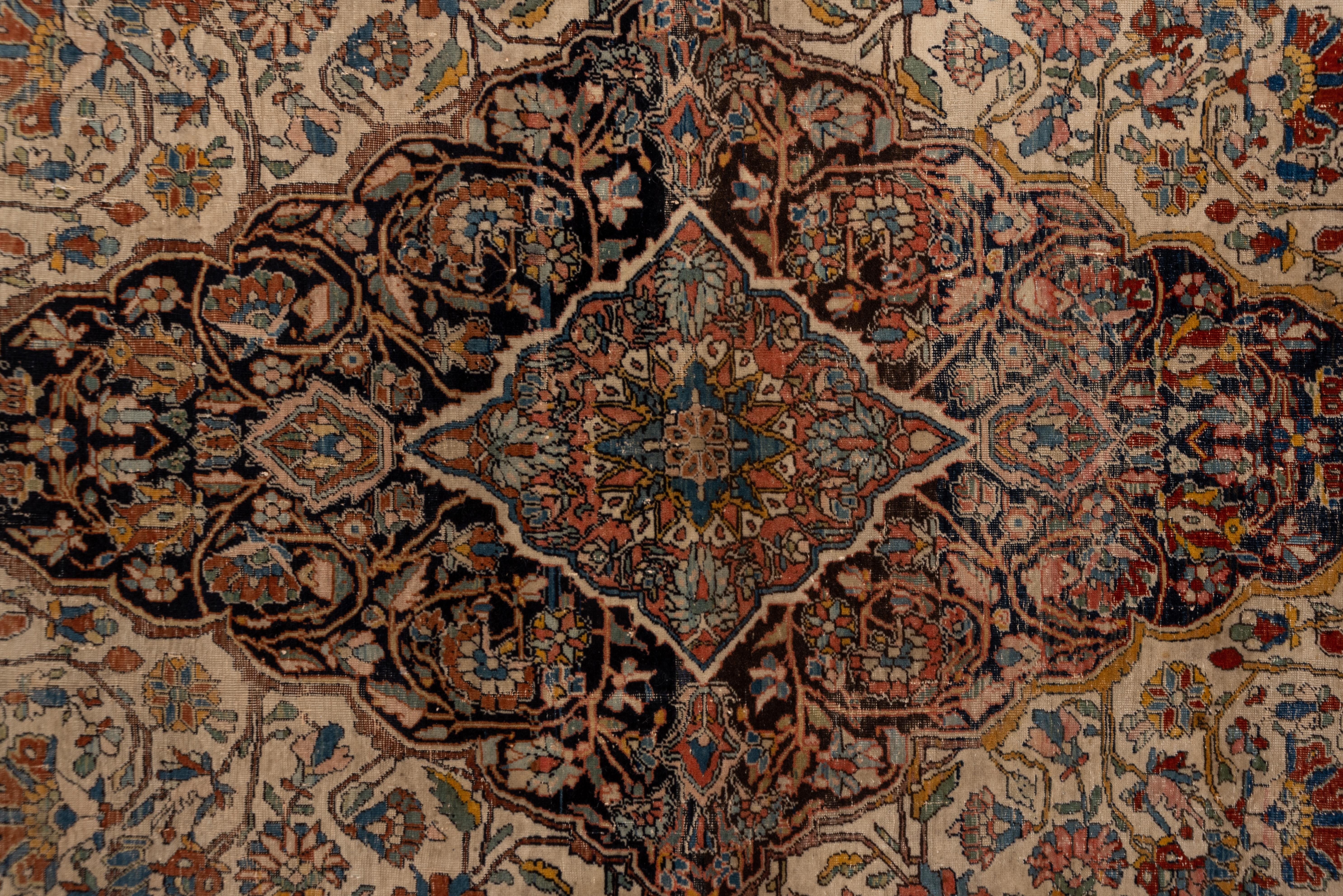 Ce tapis de ville antique, finement tissé, de Perse centrale, présente un médaillon festonné, légèrement abrasé, à palmette marine, centré sur un sous-médaillon rose, le tout sur un champ crème avec un décor en suite. La bordure crème présente de