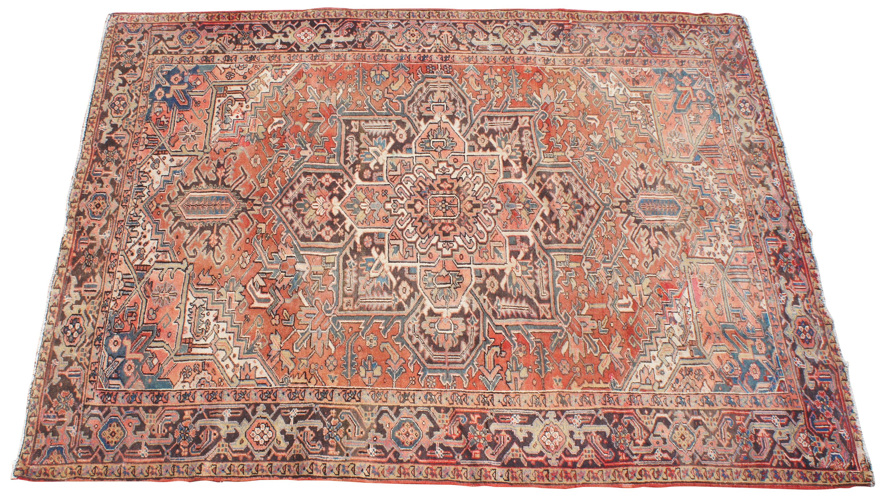Antique hand knotted Oriental Heriz area rug made in Persia. Features a field of reds / pinks / peach with a floral throughout motif, geometric diamond shapes, and large central layered medallions. Multiple boarders encompass various intricate