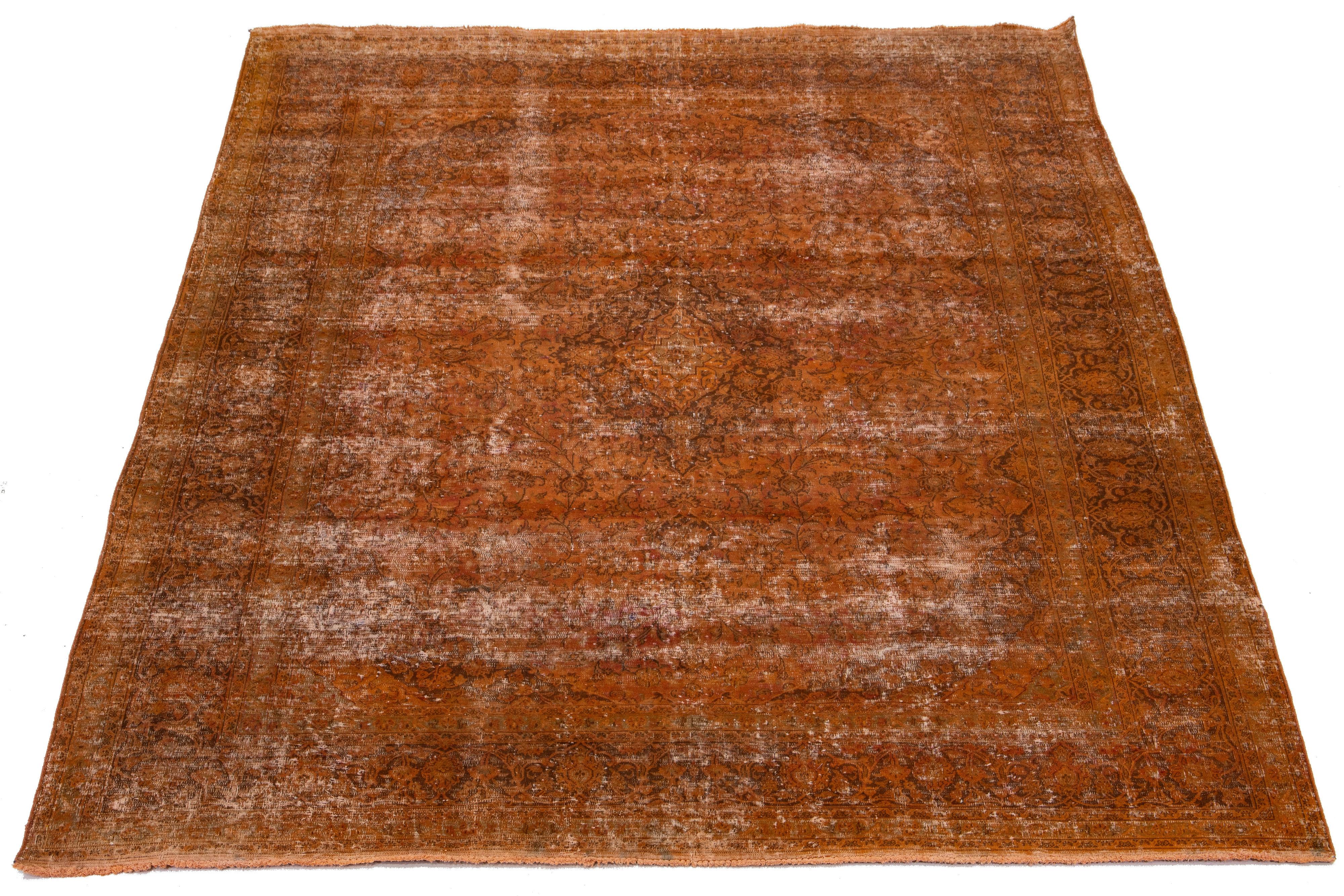 This orange, antique, hand-knotted Persian wool rug has a medallion floral design with brown and beige accents.

This rug measures 9'9'' x 12'6
