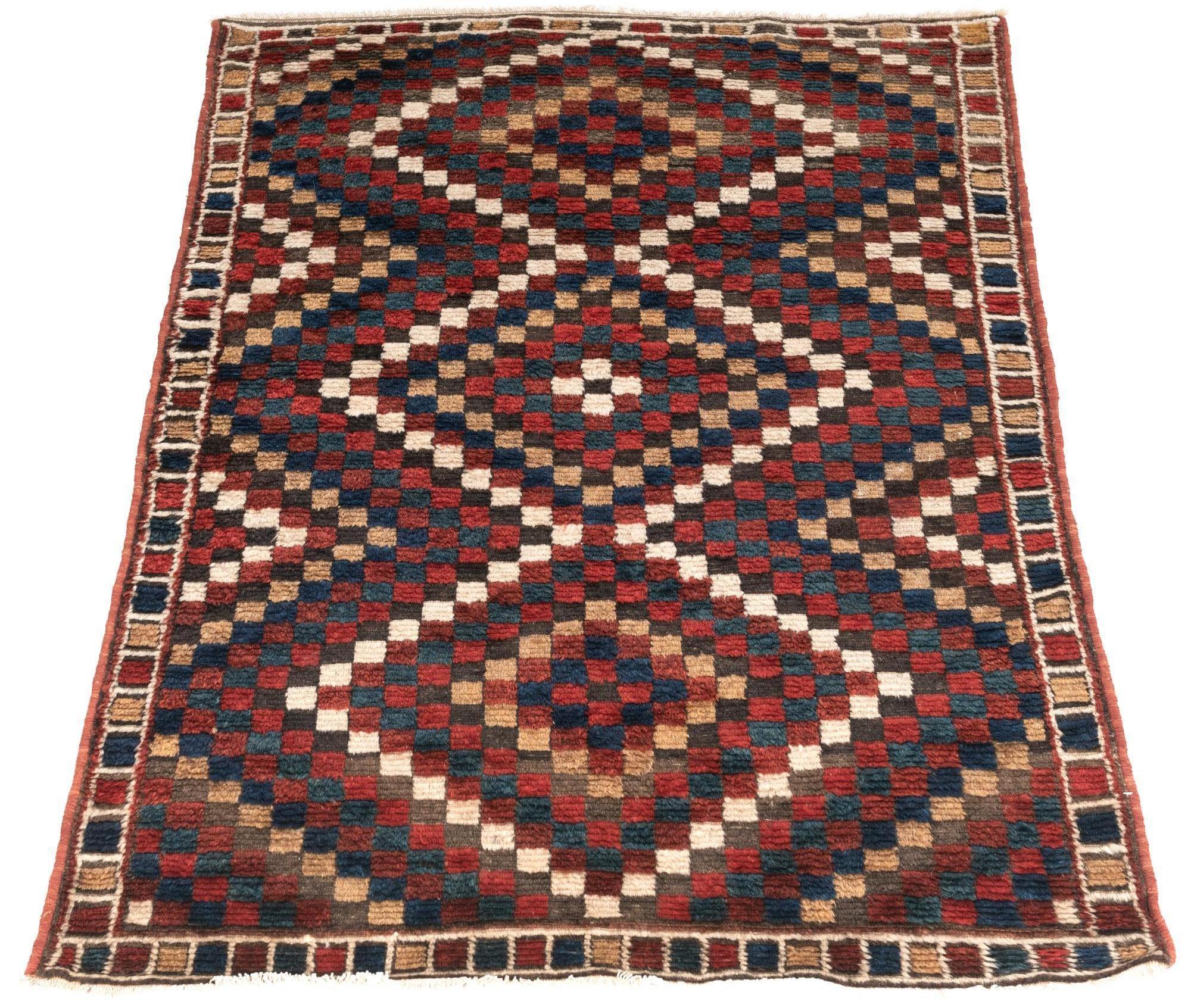 This antique Persian carpet was woven with thick wool by the Lori Tribe of Southwestern Persia. The main field is covered with a small geometric pattern with alternating colors that runs through the length of the carpet. The narrow border is