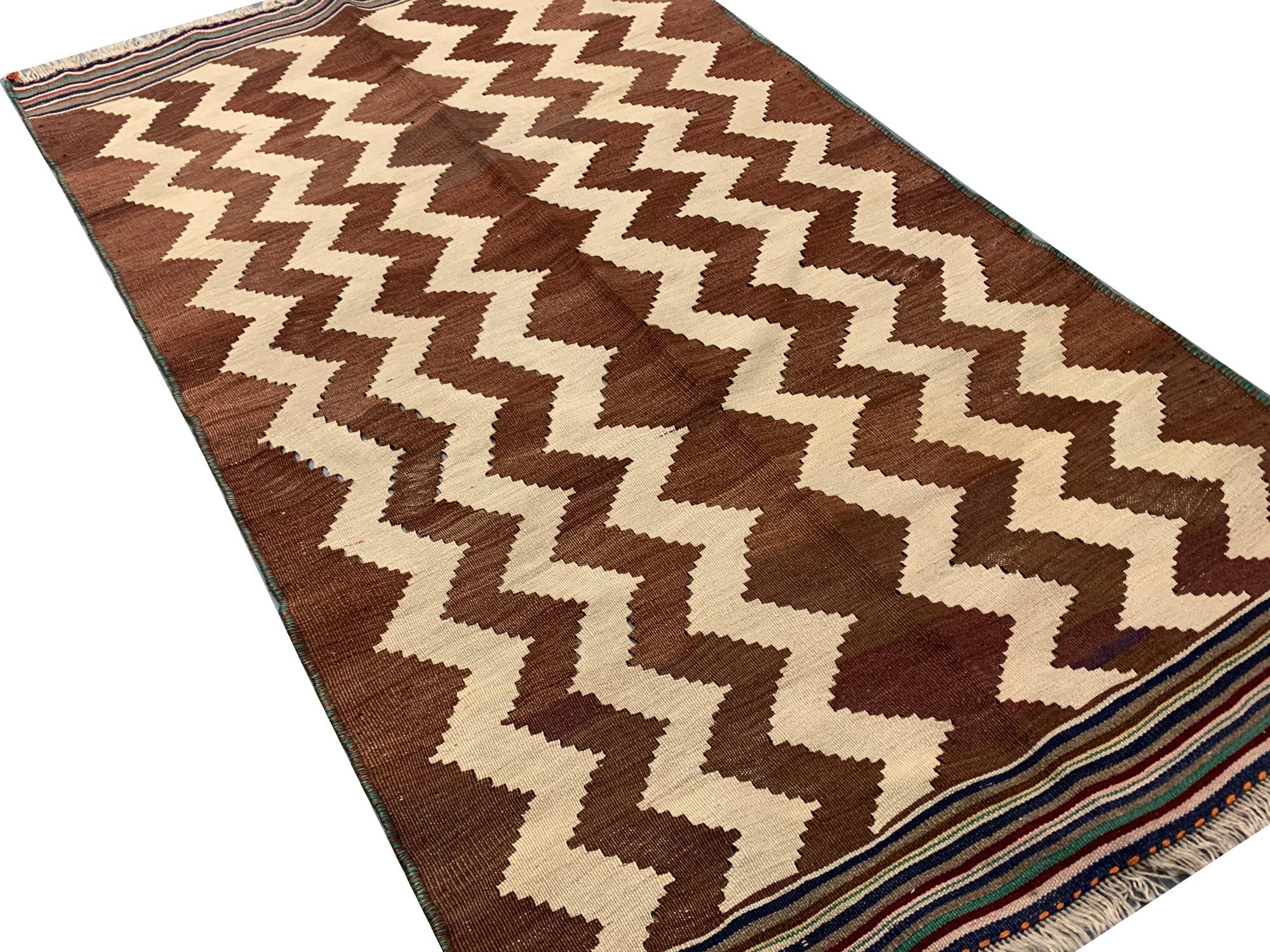 Crafted with meticulous hand-knotting, boasts a fusion of tradition and timeless elegance. The weave exudes a sense of authenticity, setting it apart as a truly exceptional find. The pattern is woven on a brown background and features beige and