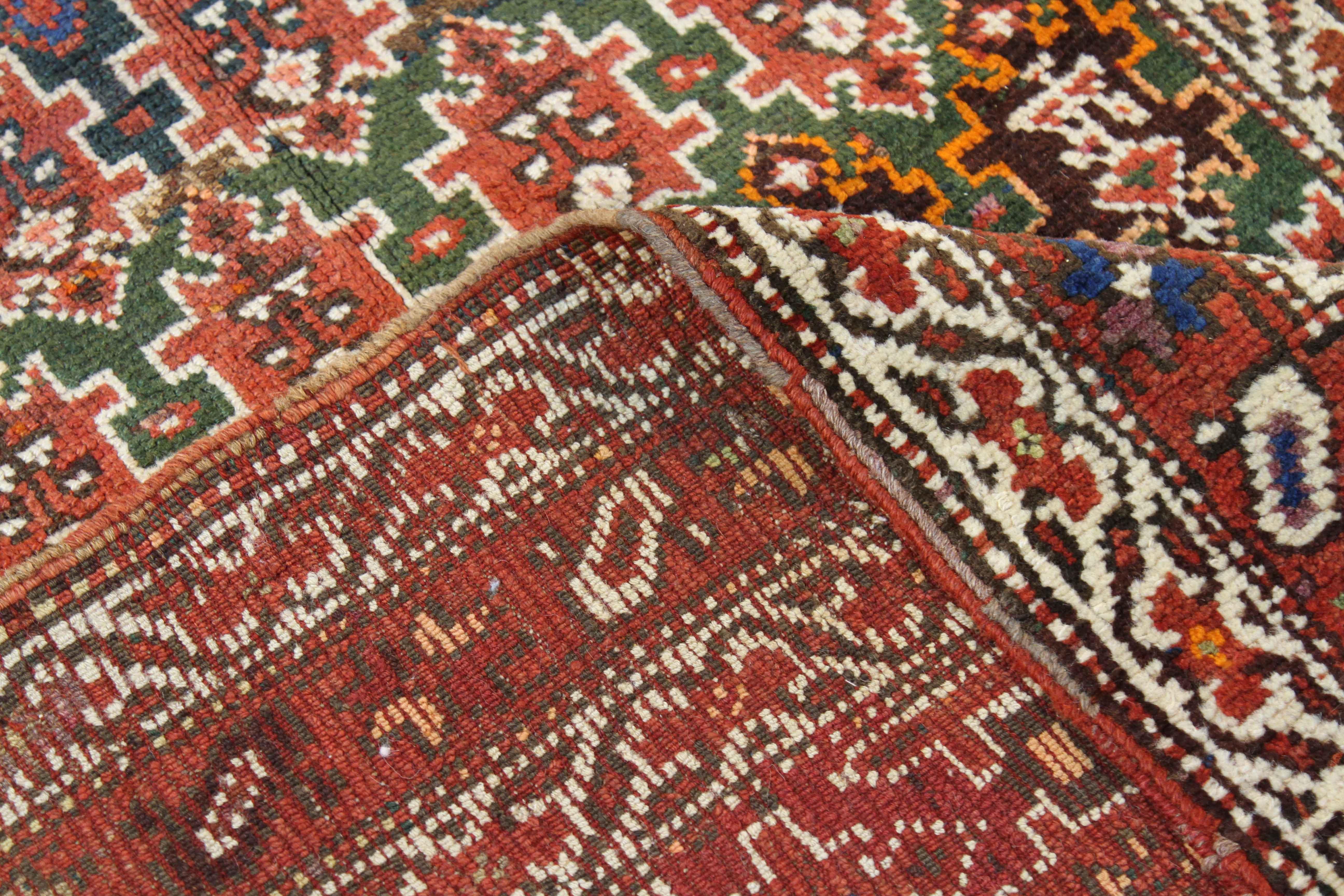 Made of handspun wool and organic vegetable dyes, this antique Persian rug showcases colorful repeating tribal patterns identified with Azerbaijan weaving. It has a color mix of green, red, navy and brown giving it a more traditional vibe. It’s